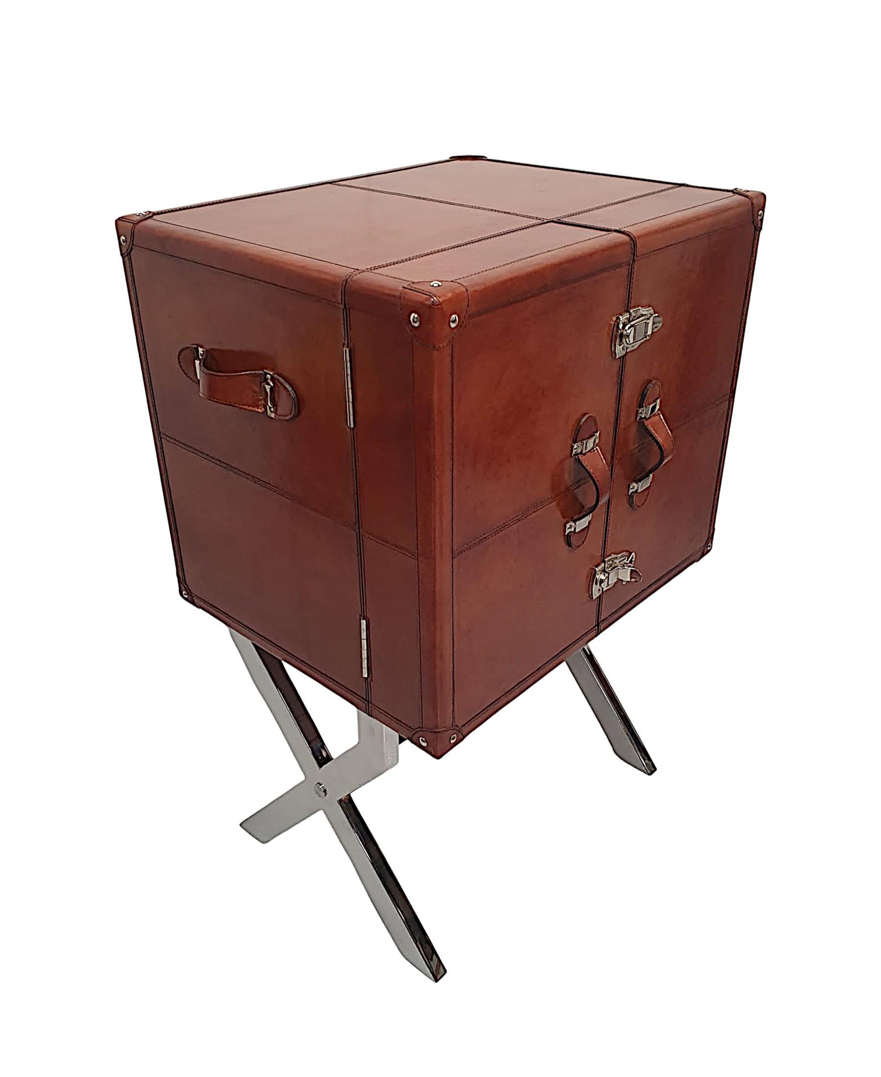 A fine leather and chrome drinks cabinet of exceptional quality and beautifully covered in elegant tan leather upholstery.  The moulded top is raised over two double doors fitted with leather strap pulls and chrome fasteners, opening to reveal a
