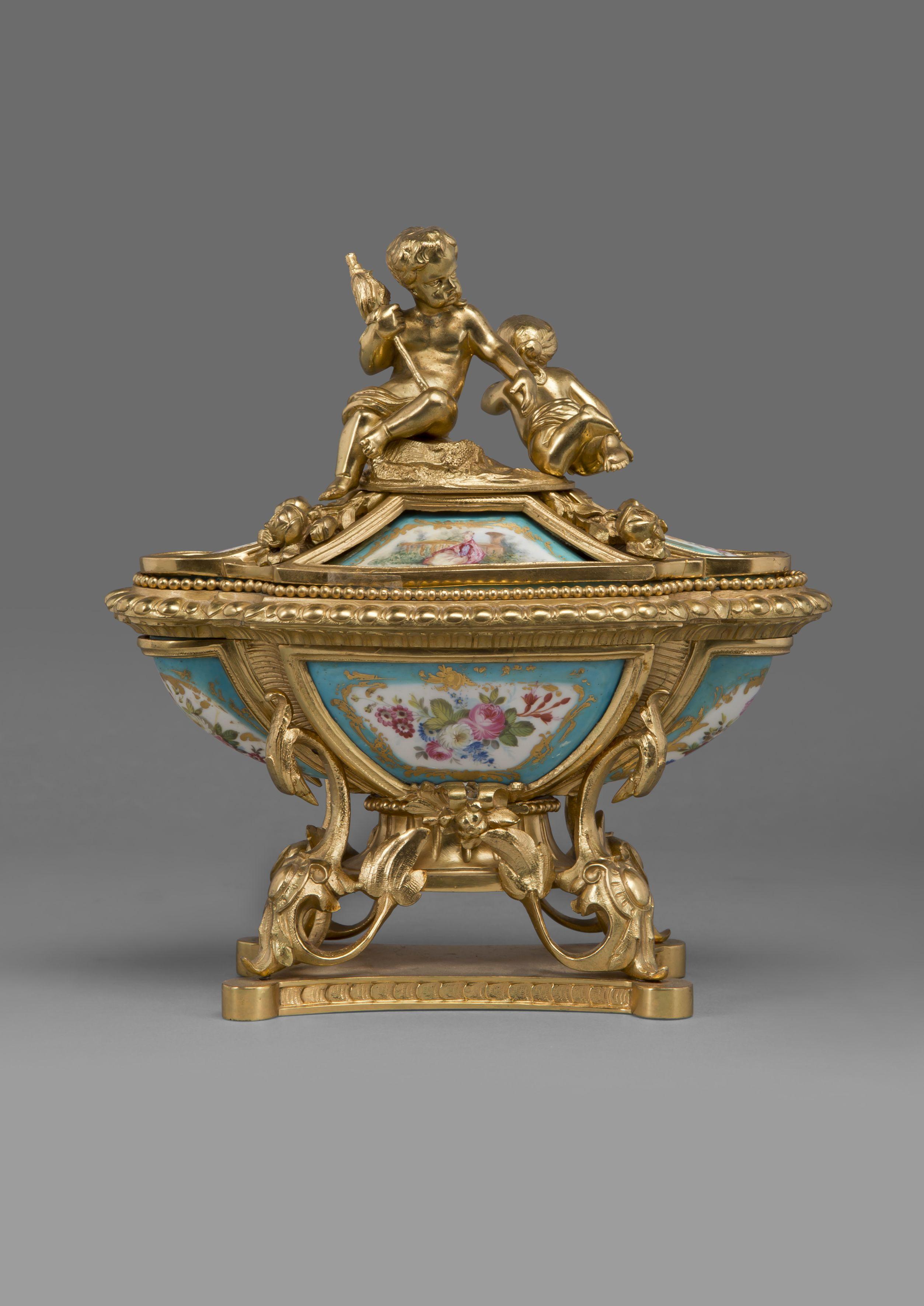 A fine Louis XV Style gilt bronze and Sèvres style Porcelain inkwell.

French, circa 1890. 

This elegant and sophisticated inkwell is of sarcophagus form with finely painted porcelain panels depicting la fête champêtre and foliate sprays, the