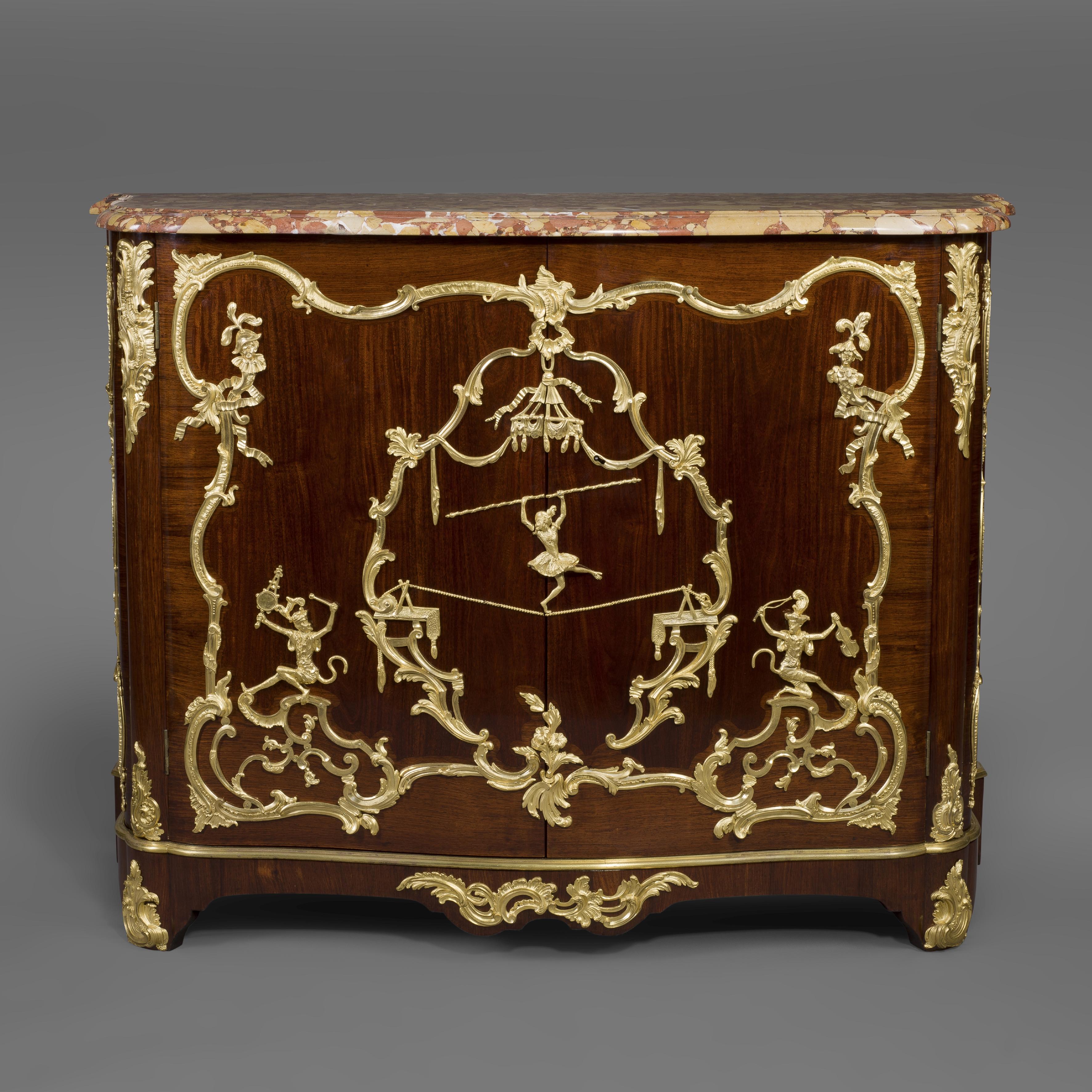 A fine Louis XV style gilt-bronze Mounted Mahogany side-cabinet in the manner of Charles Cressent, Attributed to François Linke.

This fine side cabinet or 'Bas d'Armoire aux singes' has a Brèche d’Alep marble top above a pair of cupboard doors