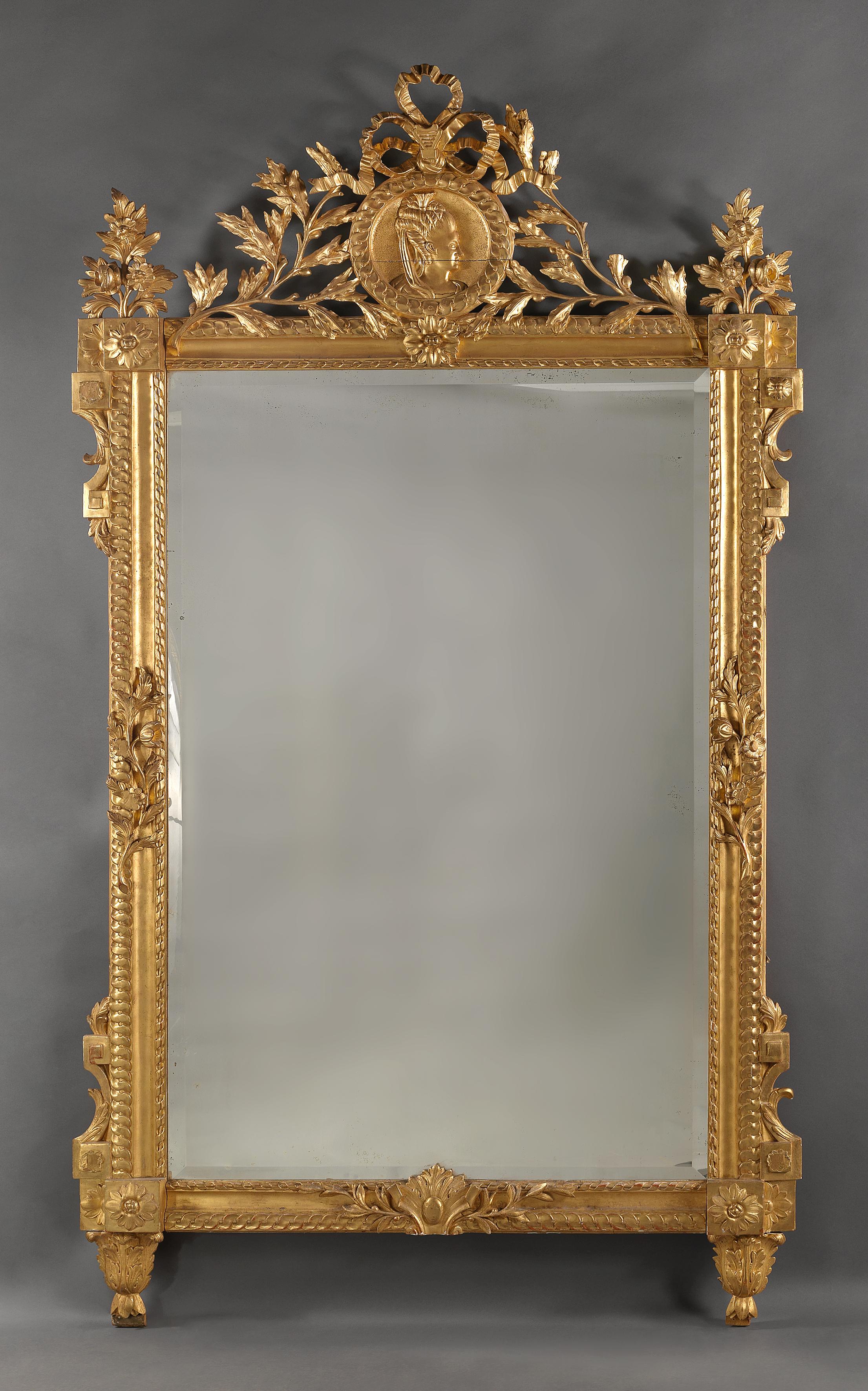 A fine Louis XVI style carved giltwood mirror, the cresting carved with a portrait roundel of a young woman in profile.

French, circa 1890. 

This impressive mirror is richly carved with a ribbon tied laurel cresting centred by a guilloche
