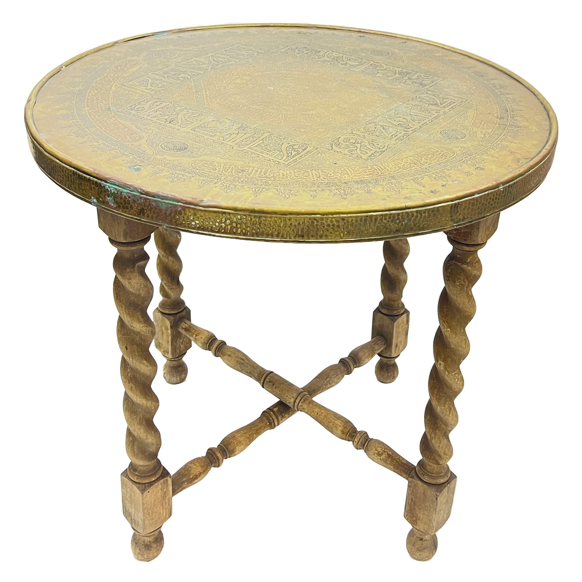 Late 19th century heavily carved Islamic calligraphy and Mamluk motifs brass centre table, the brass top of a round shape raised on a four spiral columns wooden base. Egypt or Syria.
 