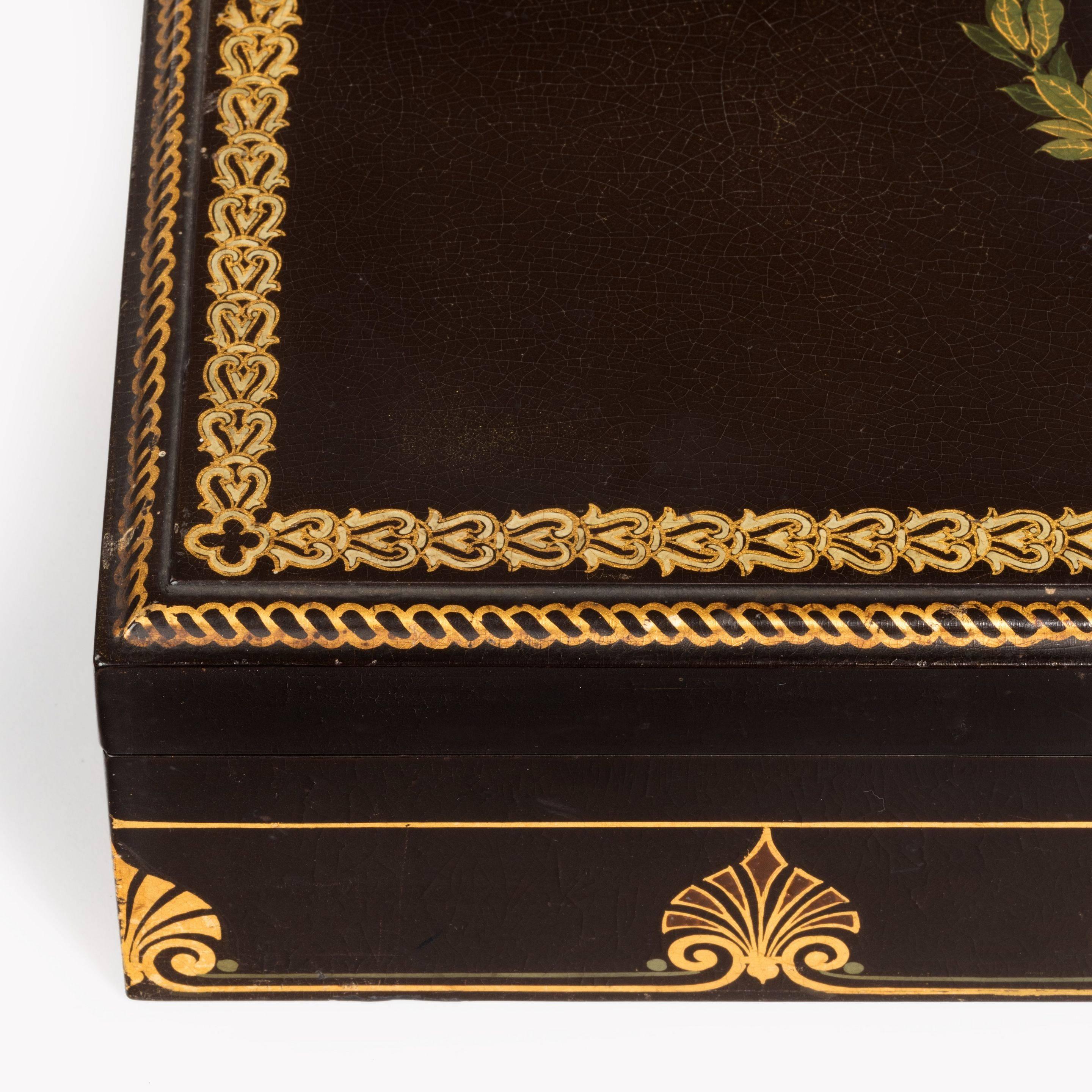 A fine mid-Victorian papier mâché box by Jennens & Bettridge with a silver medallion by Pinches, of rectangular form with a hinged lid and gilt and painted decoration of palmettes, guilloche bands and a central laurel wreath enclosing a solid silver