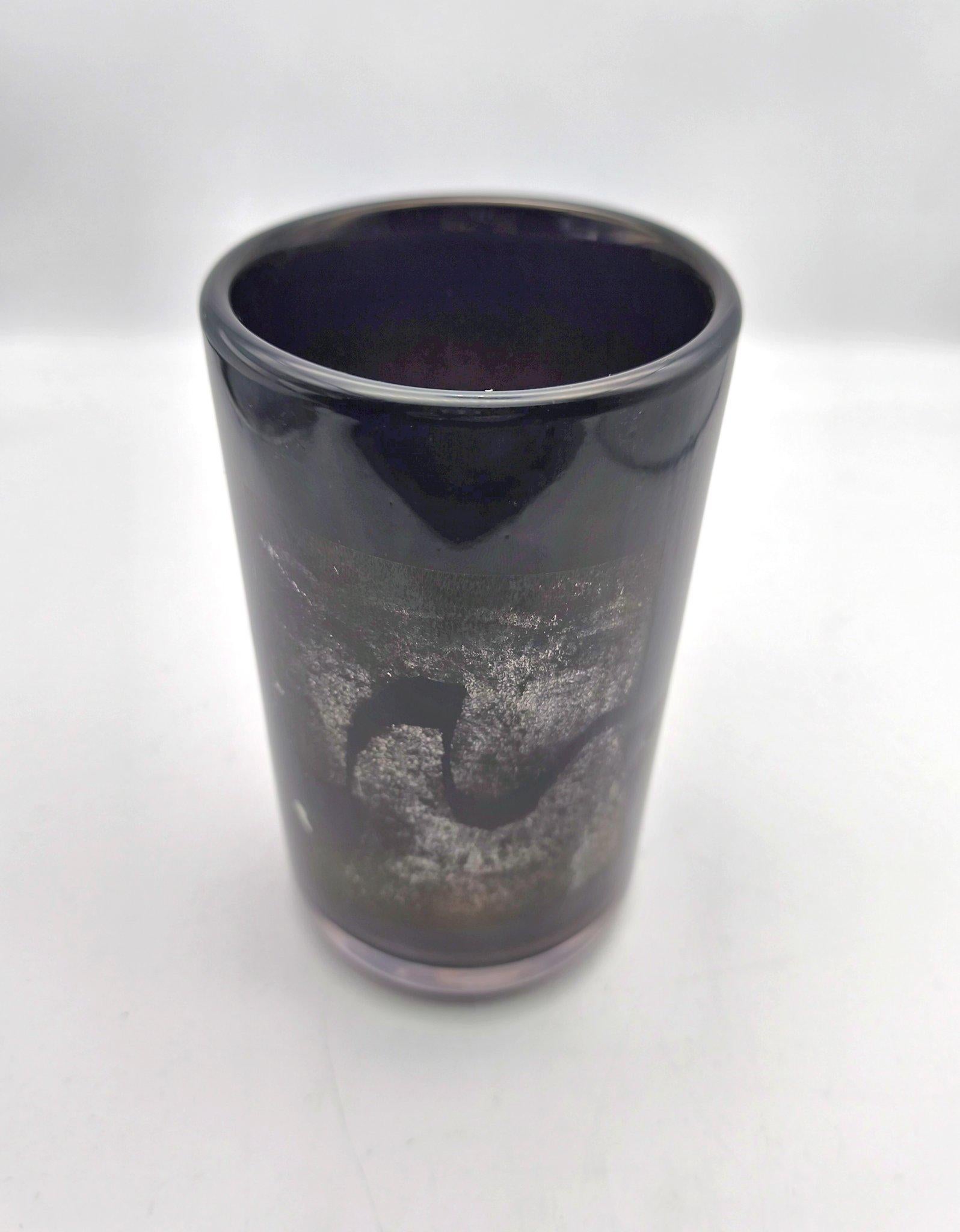A fine Mieke Groot studio glass vase from 1983. Clear glass with a dark violett inner layer. Decorated with pieces of applied silver foil, crackled up during blowing the piece to its final shape. 
Maria Margaretha Cornelia Anna Groot (born 1949) is