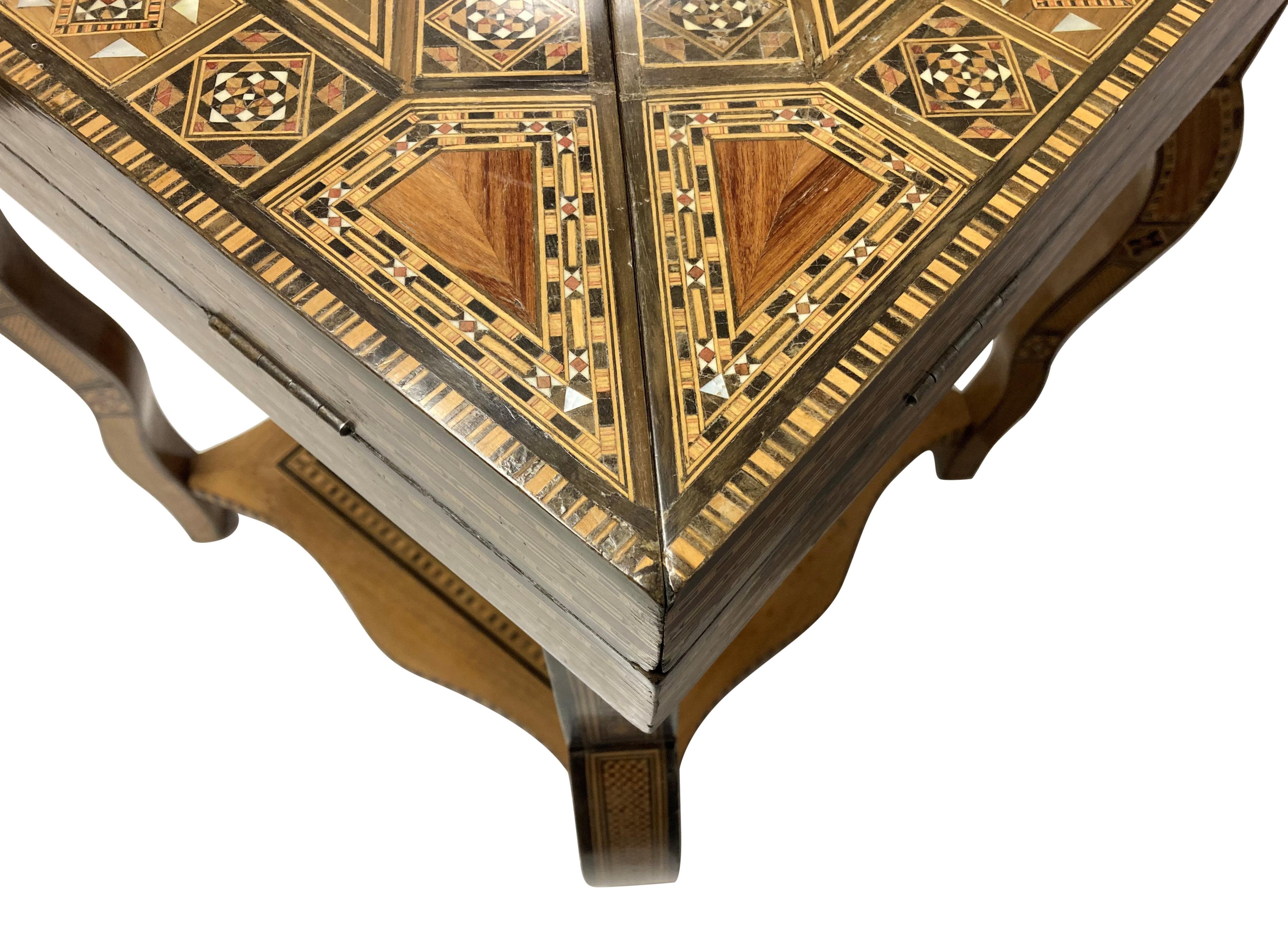 A Moorish games table of fine quality on cabriole legs, with a lower shelf and envelope top, opening to reveal various games layouts, including a card table. Comprised mainly of olive wood, with hardwood and bone micro-mosaic inlay. Beautifully