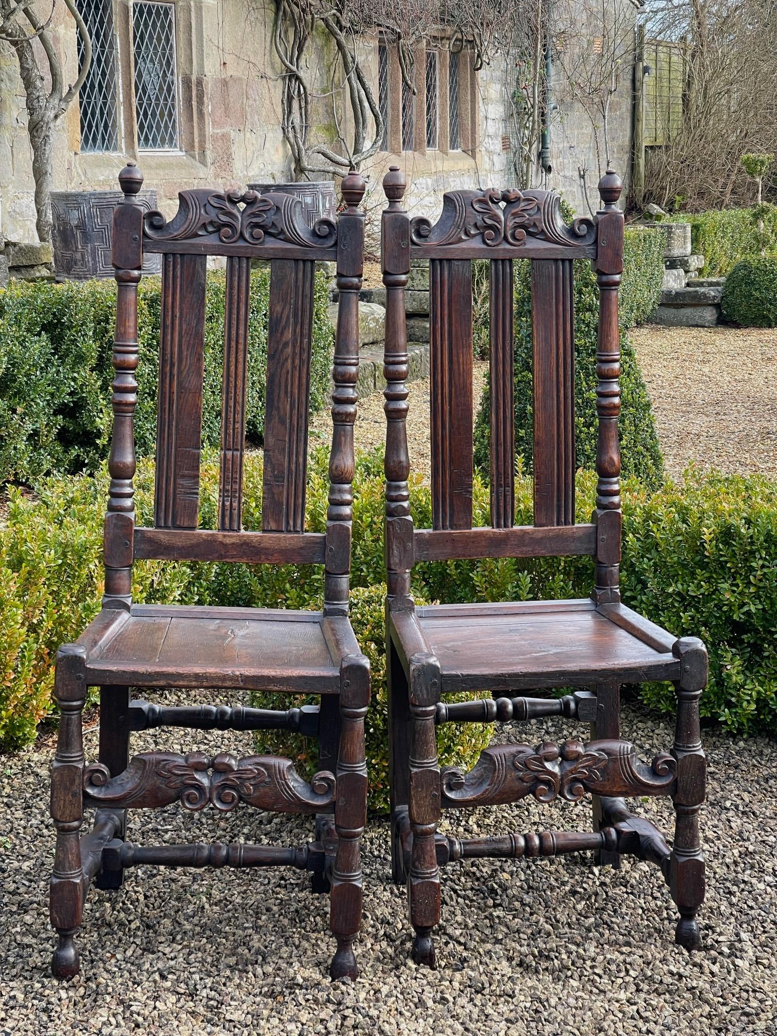 Une belle paire de chaises en chêne du 17ème siècle avec des rails en forme de crête et des extensions frontales, le tout en bonne couleur et patine.

120 cm de haut 45 cm de large siège 49 cm