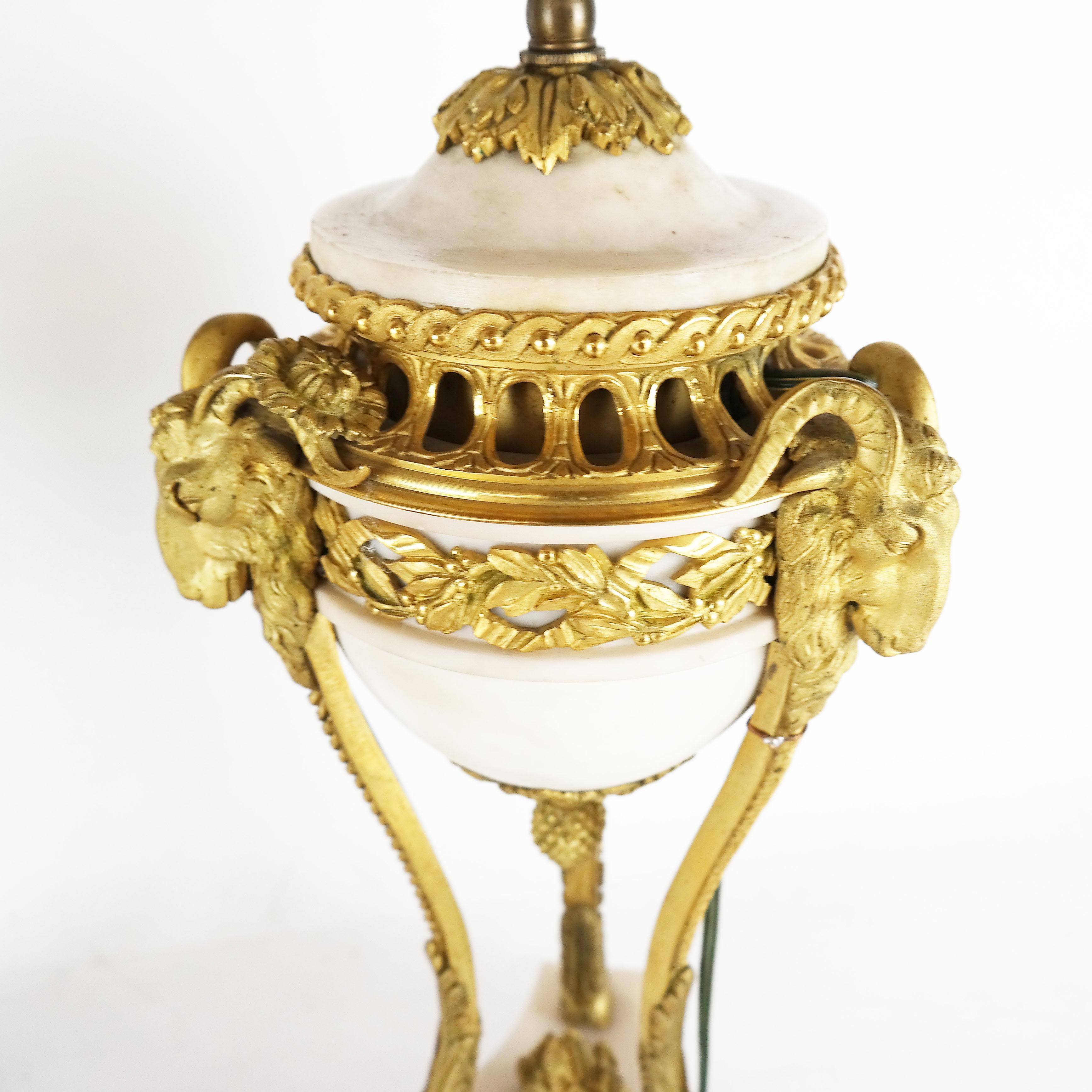 A fine pair of French 19th century Louis XVI Carrera marble and rams head gilt bronze tripod urn lamps.
