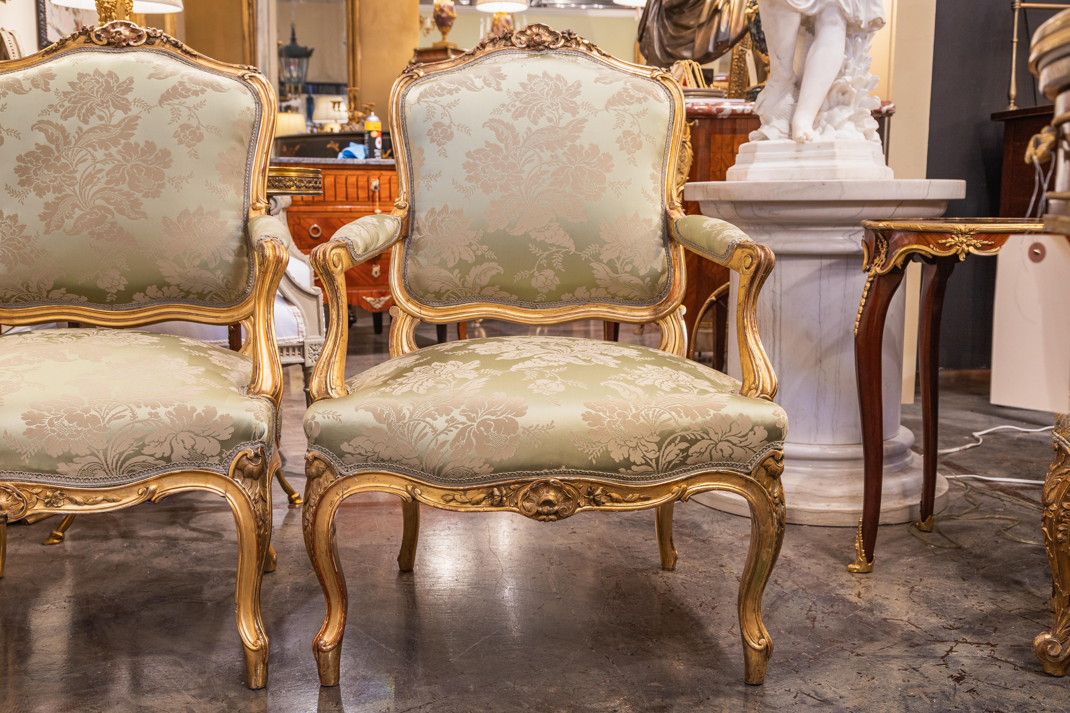 A very fine 19th century pair of Louis XV hand carved and water gilt fauteuils. Covered in a green silk material 