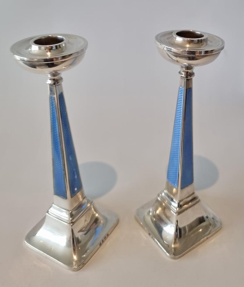 A very fine and unusual pair of Art Deco silver and guilloche enamel candlesticks. Square tapered stems with blue guilloche, engine turned enamel on all four sides and bowl shaped candle holders, on square bases. Silver marks for Goldsmiths &