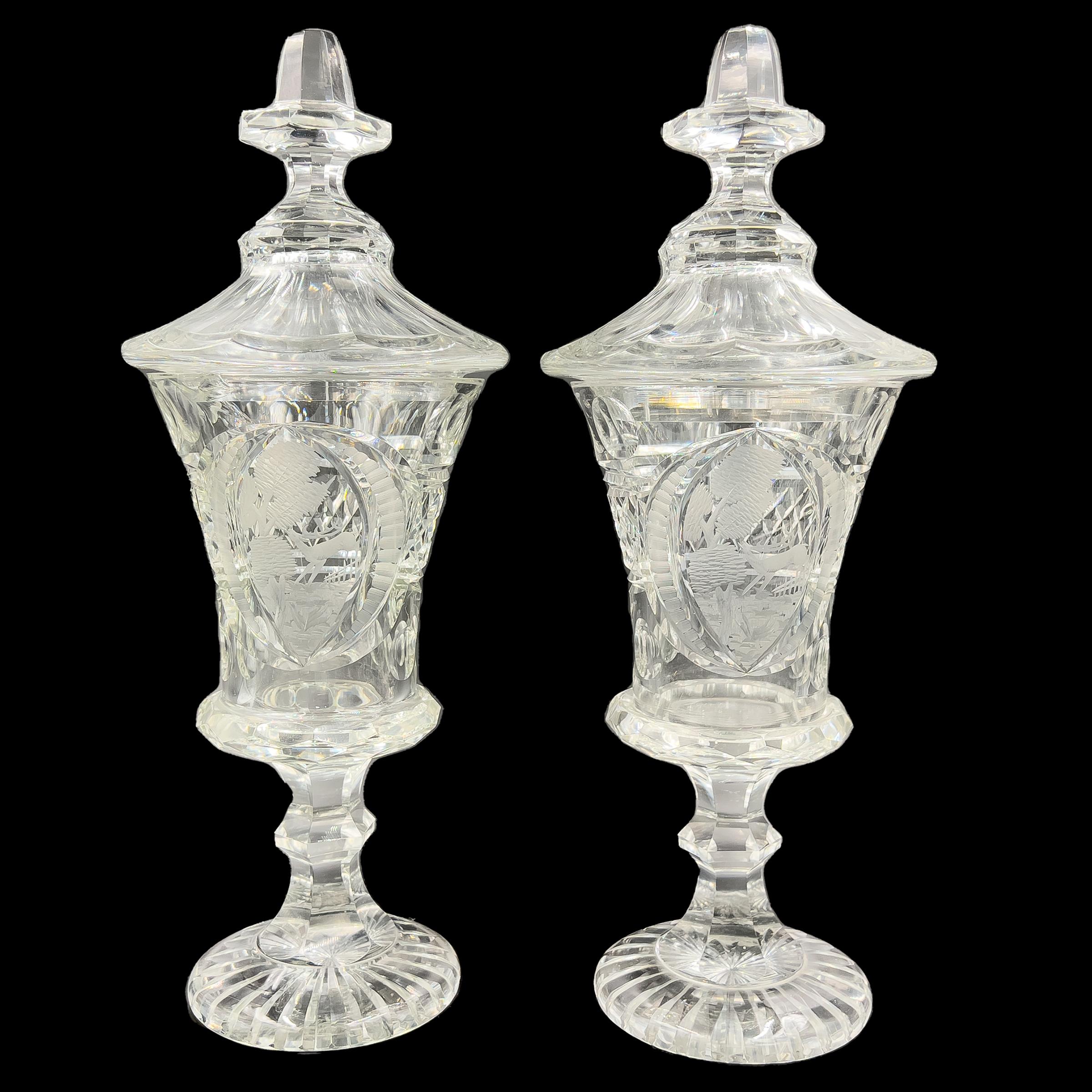 A fine pair of Bohemian clear cut glass vases, Each with a flaring domed lid surmounted by a octagonal finial, scenes of wildlife through a landscape, Raised on a hexagonal knobbed stem ending on a circular foot.
 