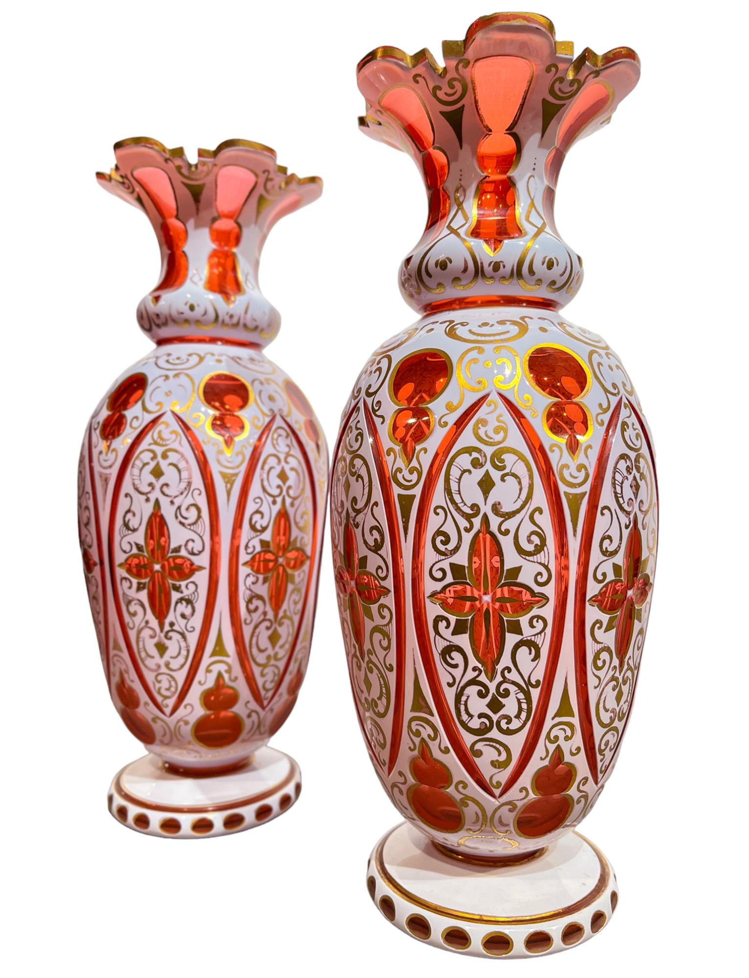 A fabulous pair of antique handmade Bohemian overlay glass vases in cherry and white. The glass overlay has been sliced into to create a gorgeous lace like pattern. Ornamented with gold paint that weaves between the elegantly sliced pattern,