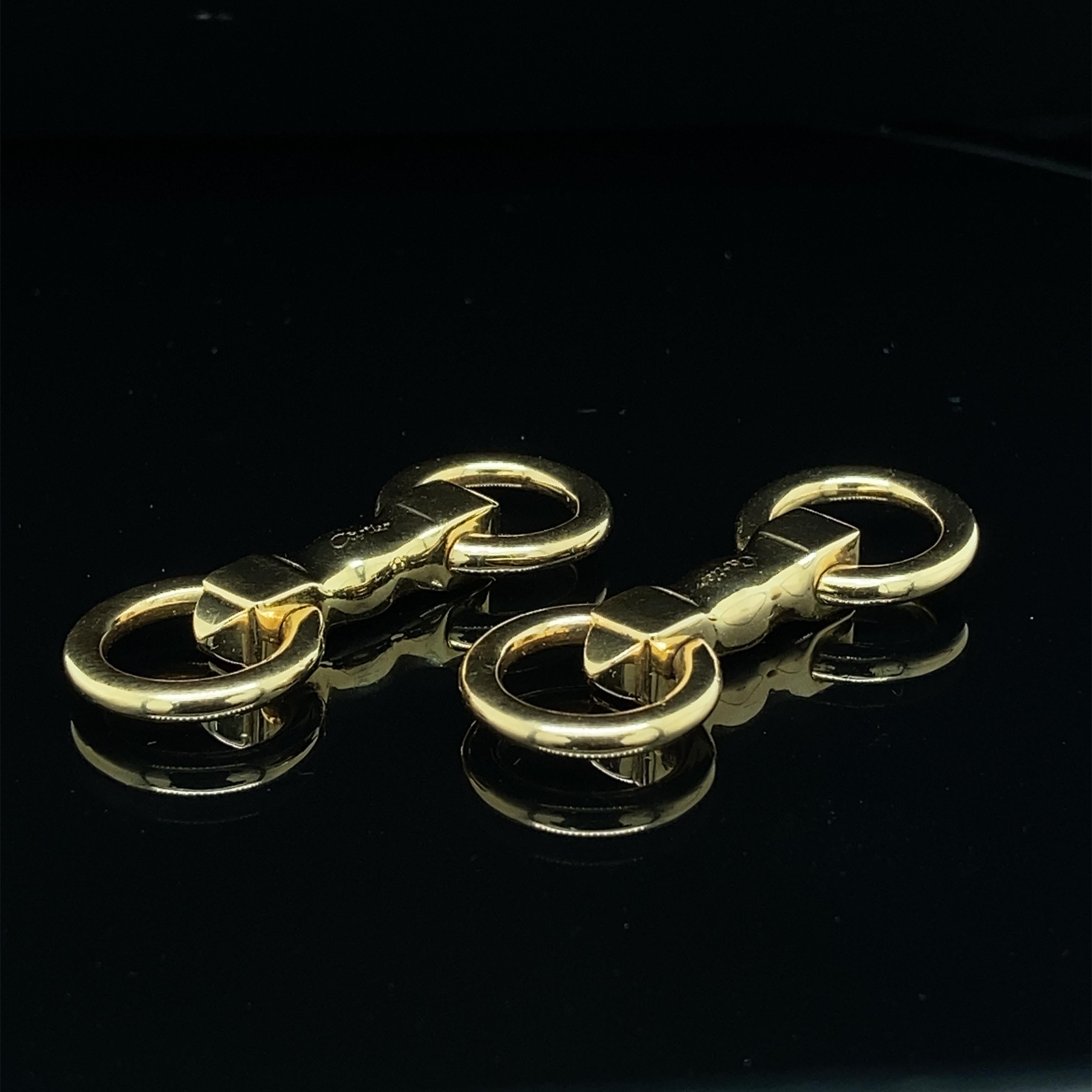 18k yellow gold Cartier cufflinks, ca 1980, each with a solid bar with pyramid-endings holding two rings with clip mechanism. 
Signed and numbered: Cartier 947795.
Length: 3.5cm
Weight: 12g
In very good condition and of very good, solid quality.