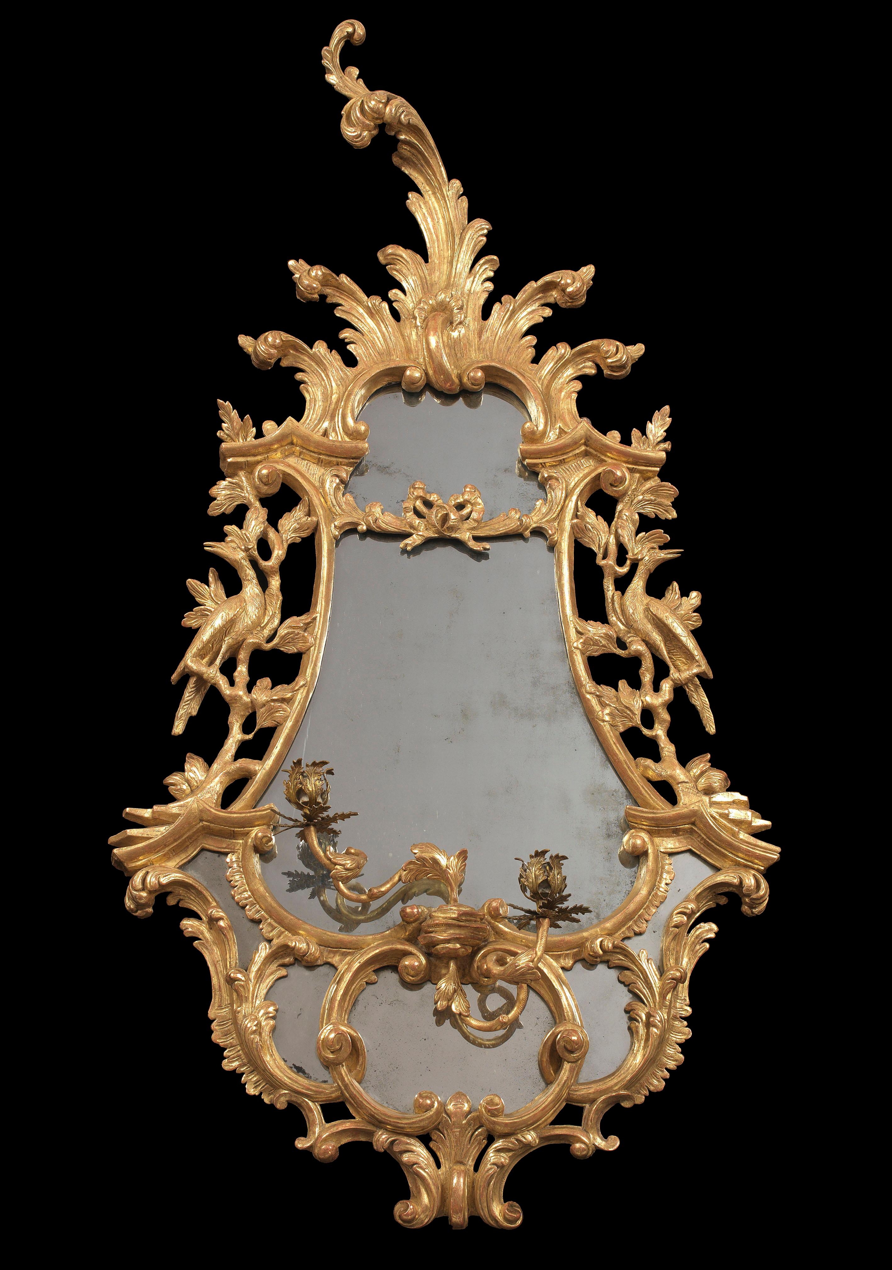 A fine pair of mid-18th century carved giltwood Chippendale period two-light girandoles; the original symmetrical plates with the divided cartouche shaped frames; the sides with scroll and foliate carving each carved with an opposing ho-ho bird;