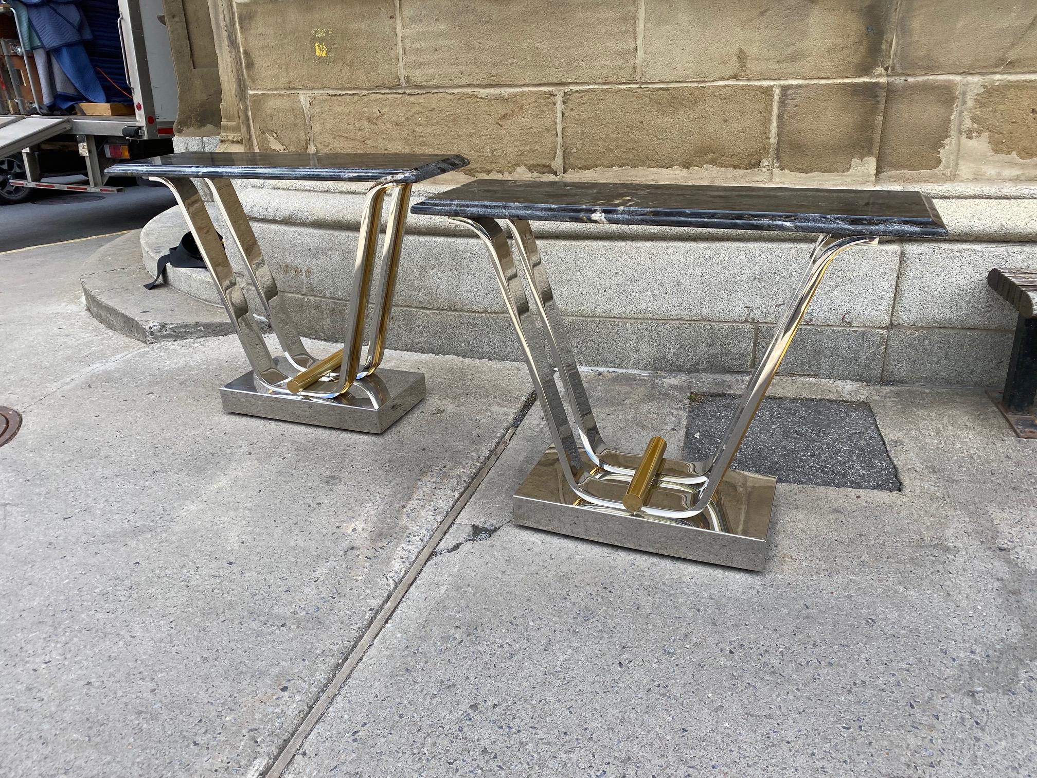 A fine pair of chromed steel and polished brass console tables by Karl Springer fitted with nicely figured granite tops. 

  