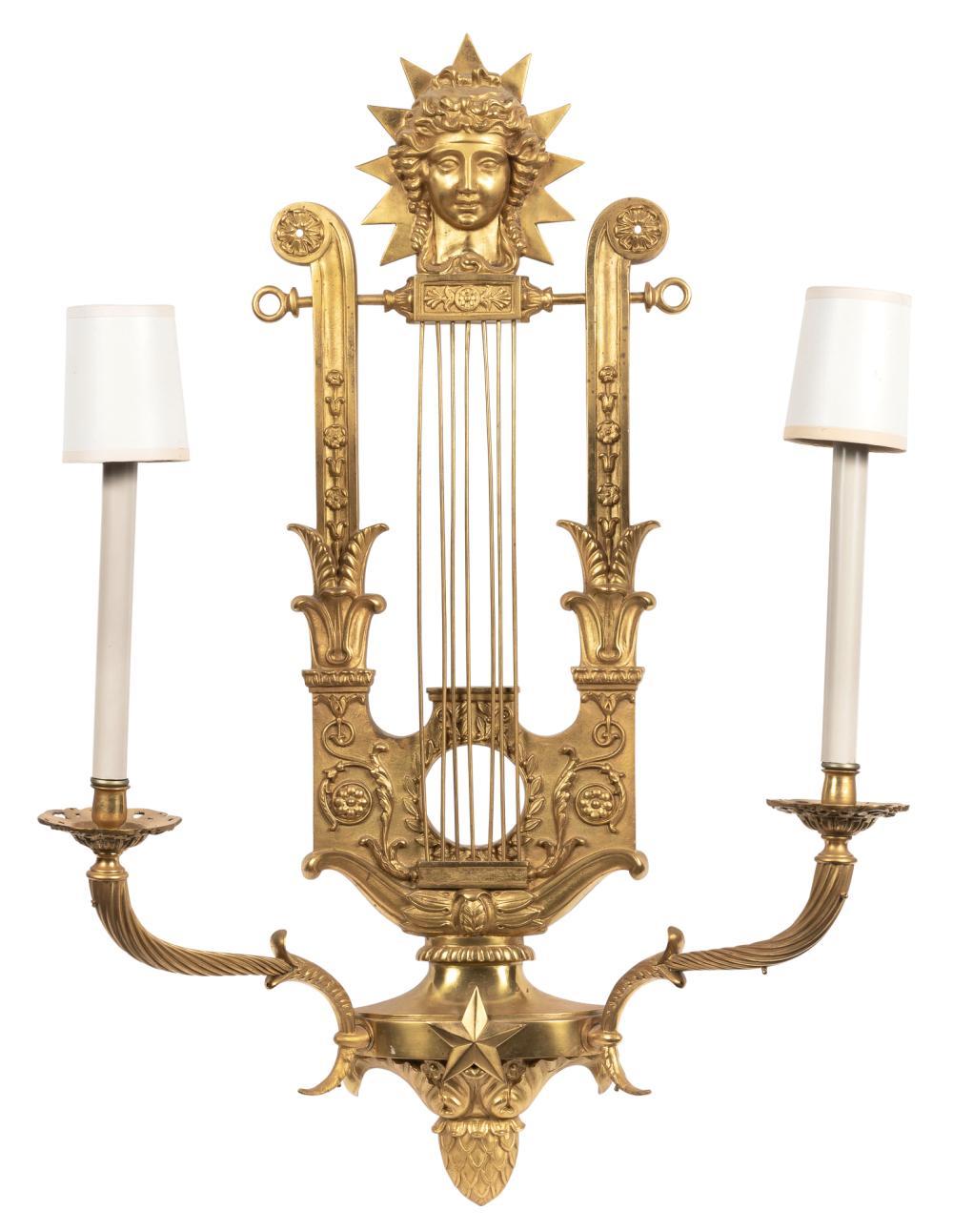 Pair of Empire style gilt-bronze two-light lyre sconces
Each pierced stringed lyre-form backplate with the mask of Apollo above two scrolling branches centered by a star over an acorn pendant.

Provenance:
Maison Tisserand, Paris.

C Property