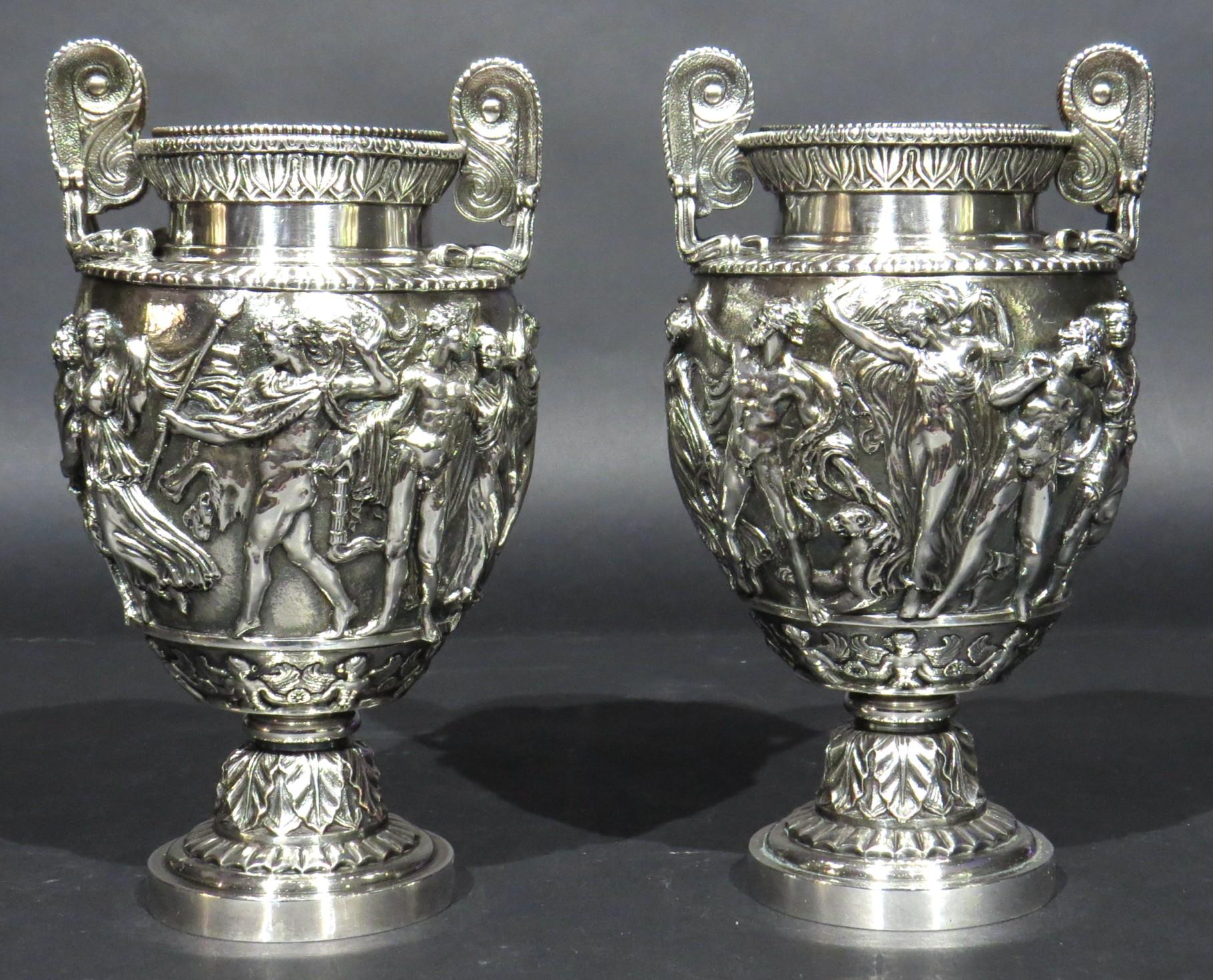 A fine pair of early 20th century silver plated Townley Vases, after the antique.
Both vases of ovoid form with volute handles, decorated overall with a Bacchanalian themed bas-relief panel depicting Bacchus holding a thyrse, followed by a