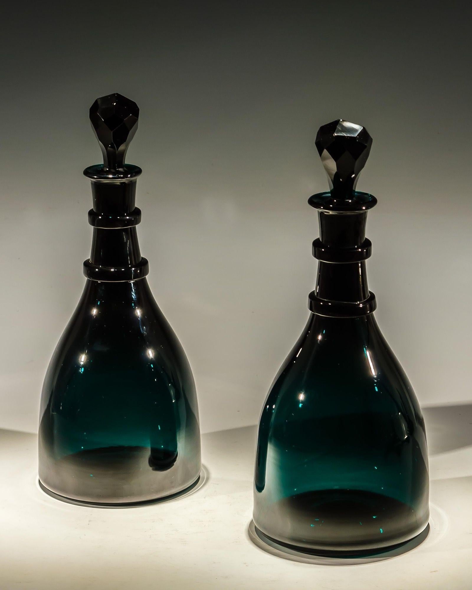 A fine pair of emerald green taper form decanters with faceted stopper.
