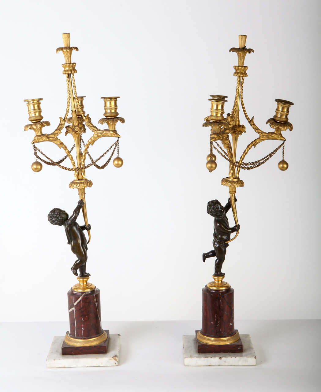 A fine pair of French 18th century bronze and gilt bronze candelabra, each in the form of putto figures holding aloft three scrolled candle-branches on a red marble and a square white marble base.
Size: cm 72 x 22.
