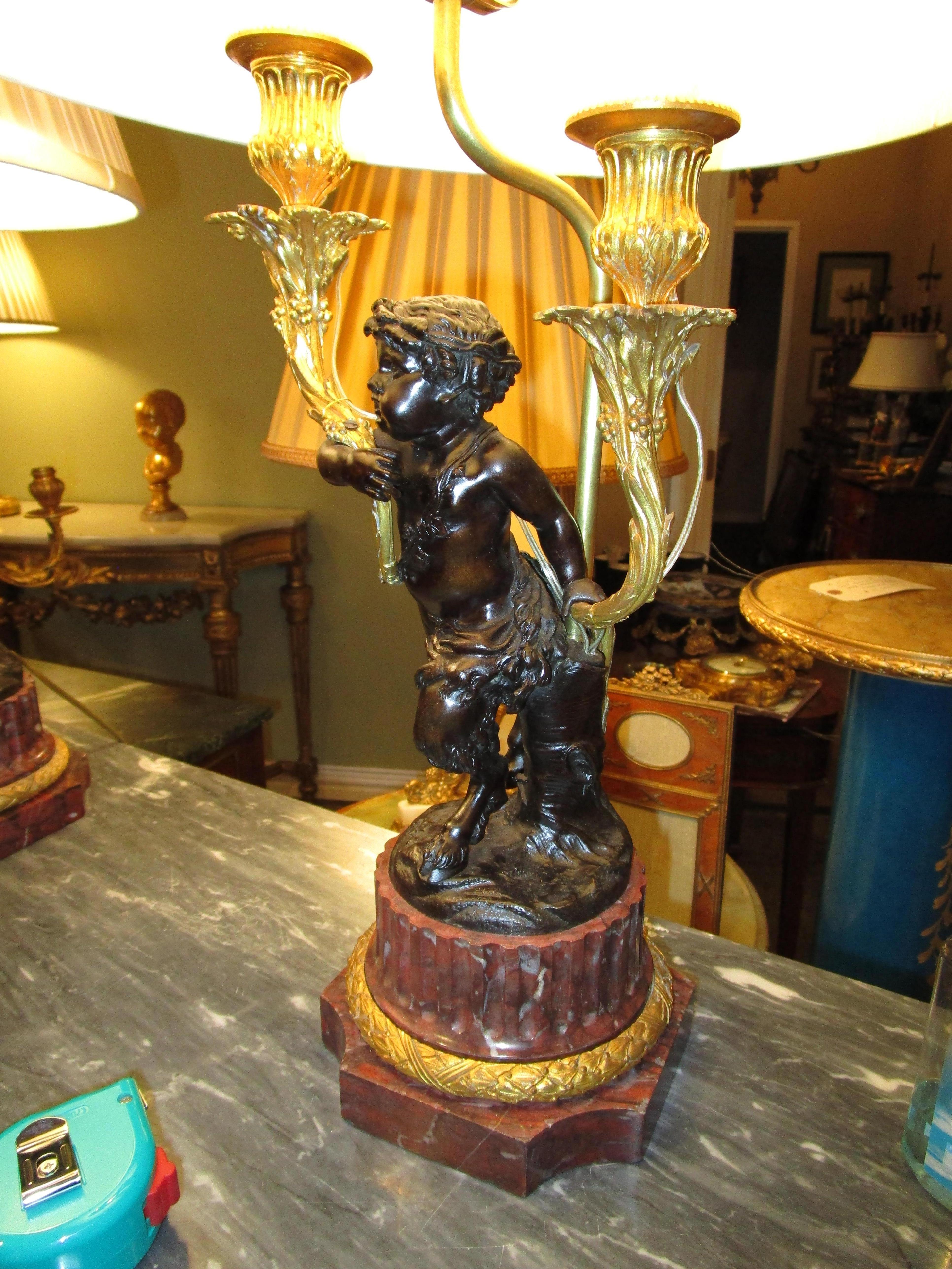 A fine pair of 19th century French Clodion style patinated bronze cherub candelabra lamps with gilt bronze details and rouge marble bases.