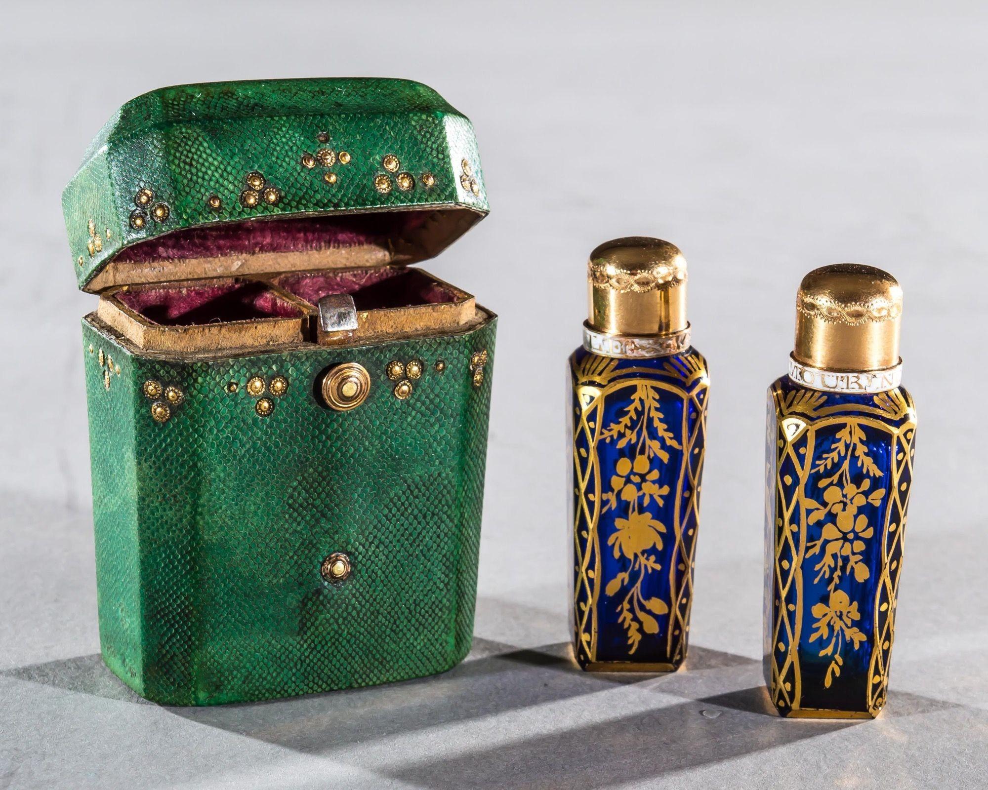 The faceted Bristol blue glass scent bottles finely gilded with birds and foliate decoration, capped by 18ct gold mounts with enamel bands, both are fitted with original stoppers in to shagreen case decorated with gilt studs.