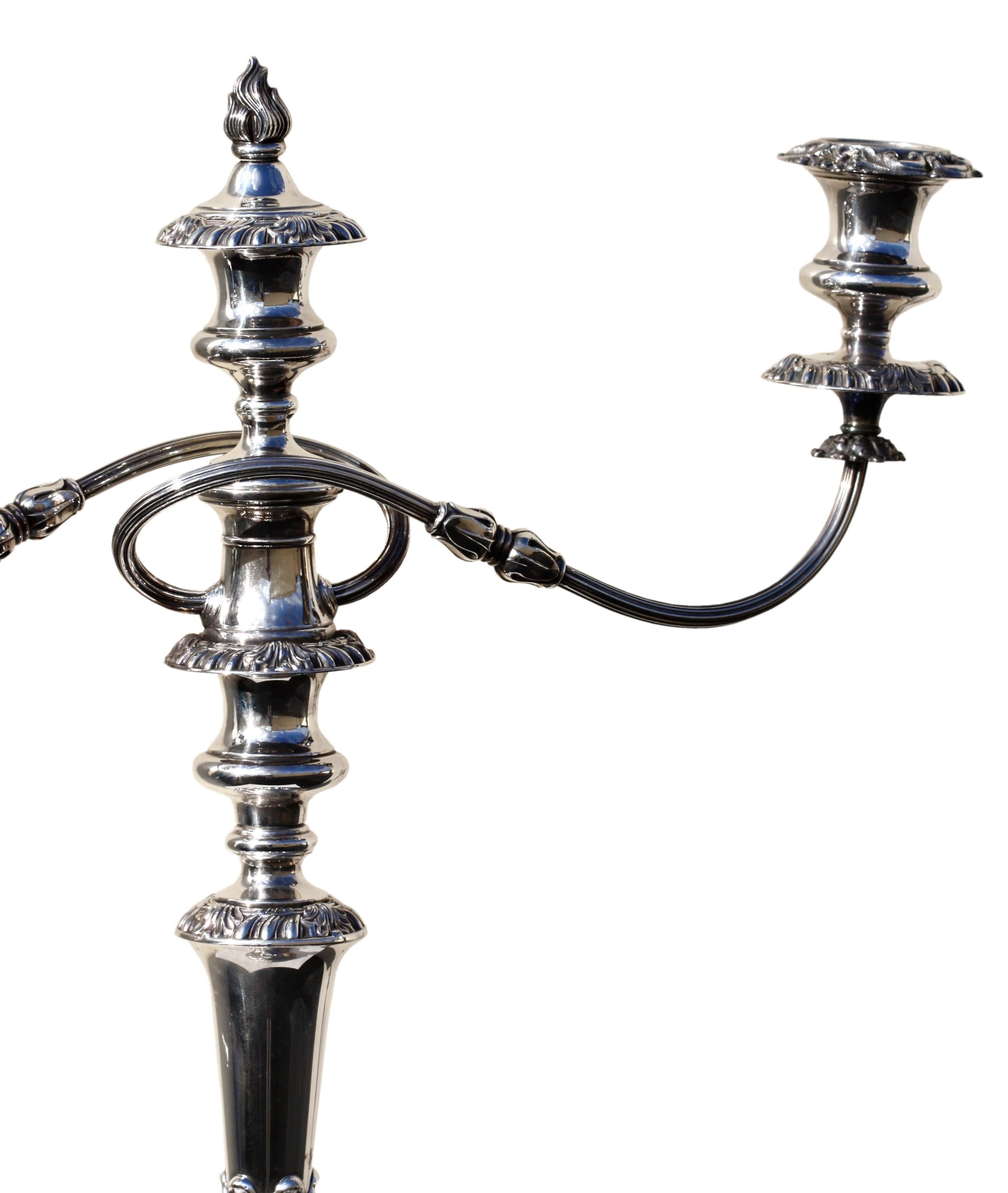 A fine pair of Georgian style silver plated three light candelabra,
English, Circa 1920. 
Maker: Ellis Baker. 
Each circular base issuing vase form stem supporting detachable reeded candle arms with urn shaped nozzles.
Height 20 3/4