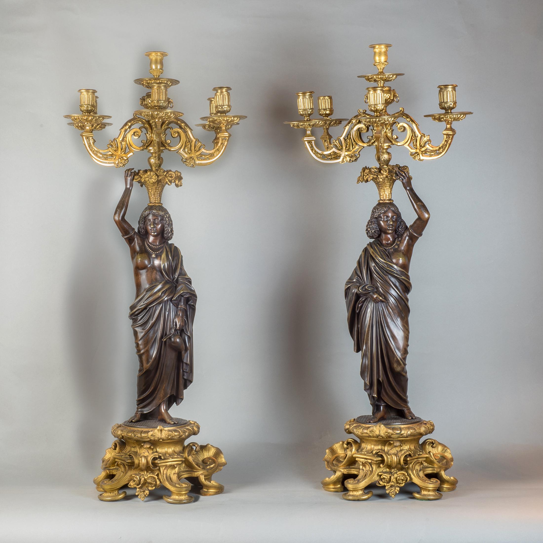 One holding a pitcher, both with six-light candelabras surmounted on floral baskets perched upon their heads, draped in necklaces.

Origin: French
Date: circa 1880
Dimension: 36 in. x 14 1/2 in.