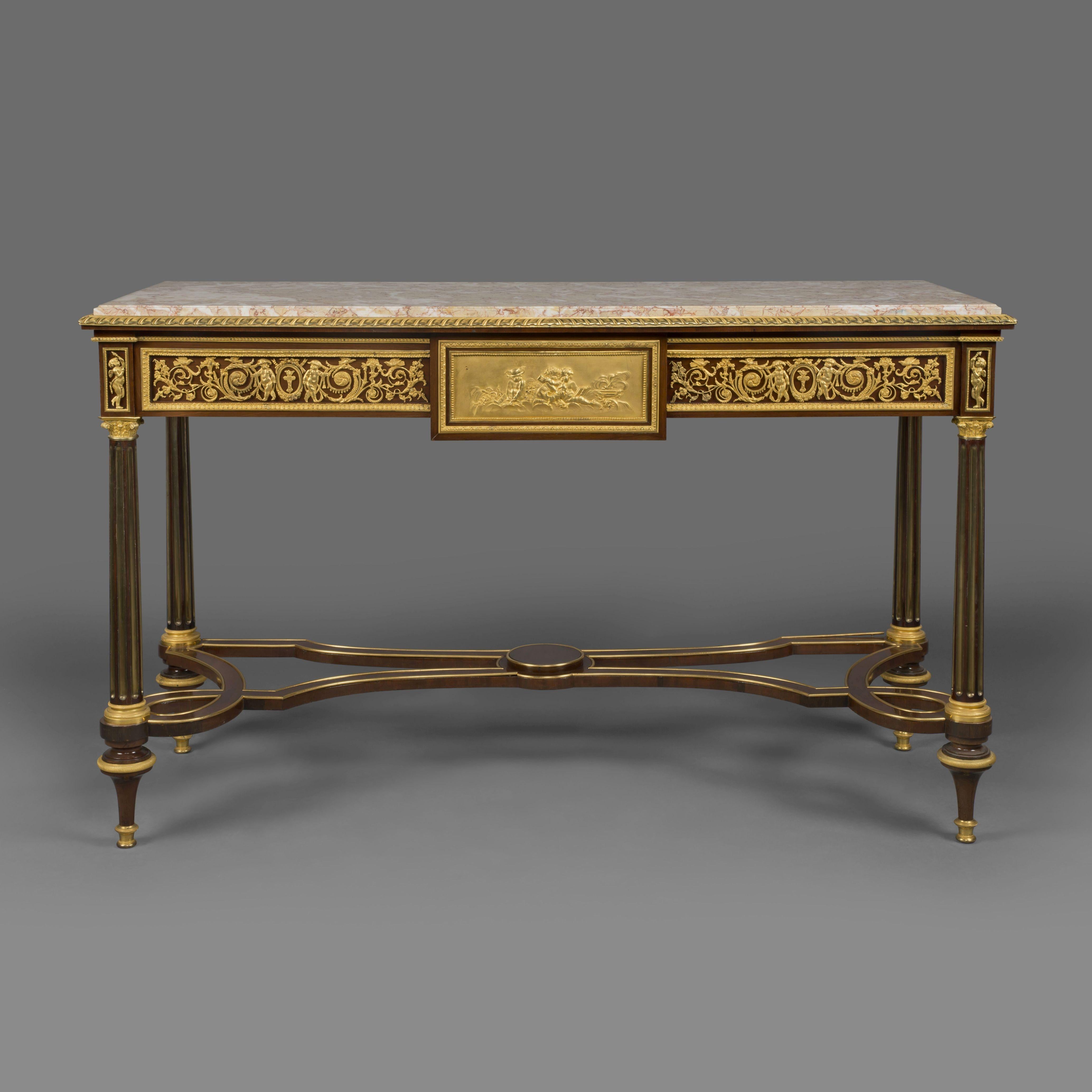 A fine pair of Louis XVI style gilt-bronze mounted mahogany console tables, in the manner of Adam Weisweiler.

Each table has a rectangular with fleur de pecher marble top above three drawers with a scrolling foliate frieze, the tables are raised