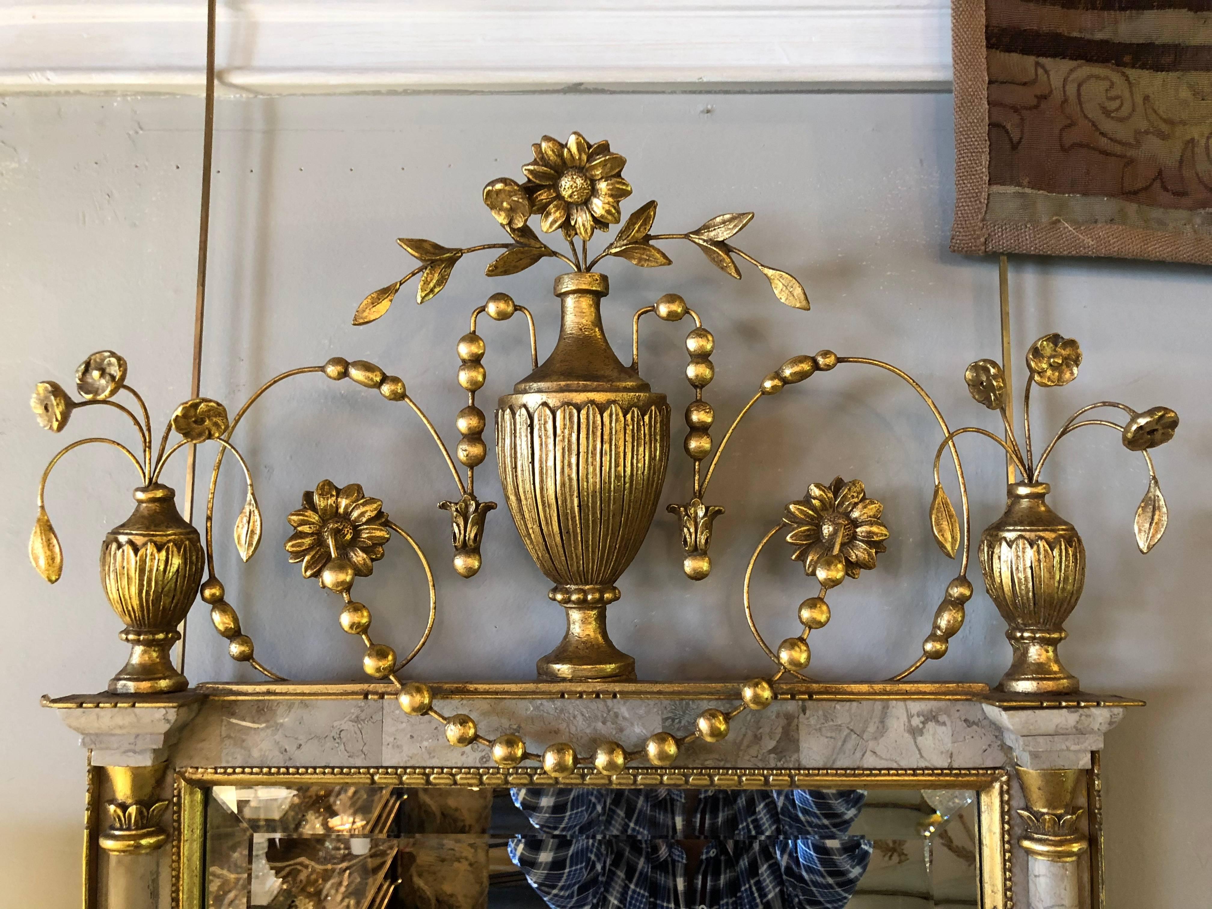 A fine pair of gilt Northern Italian wall or console mirrors. The center beveled mirror flanked by a marble column formed frame. The marble insert columns framed in a gilt gold wood carved case. The whole with fine floral leaf and vine with rose
