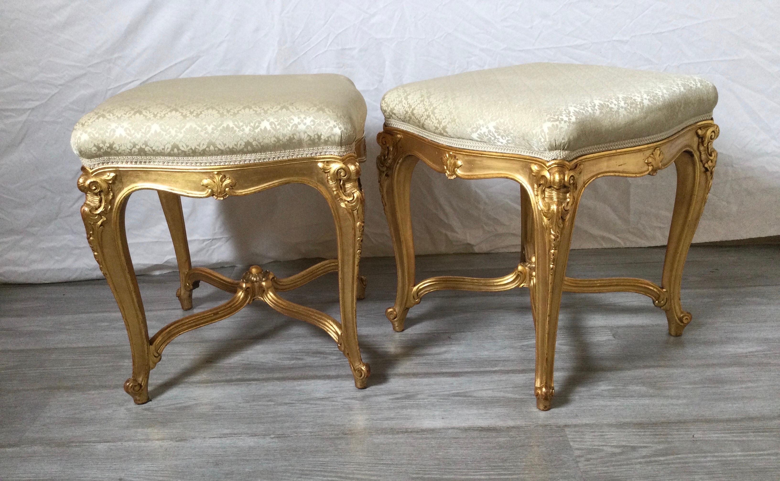 Elegant pair of giltwood Louis XV style benches. The bright gilt surface with cabriole legs with an X stretcher base. The seats in a celery green woven silk.