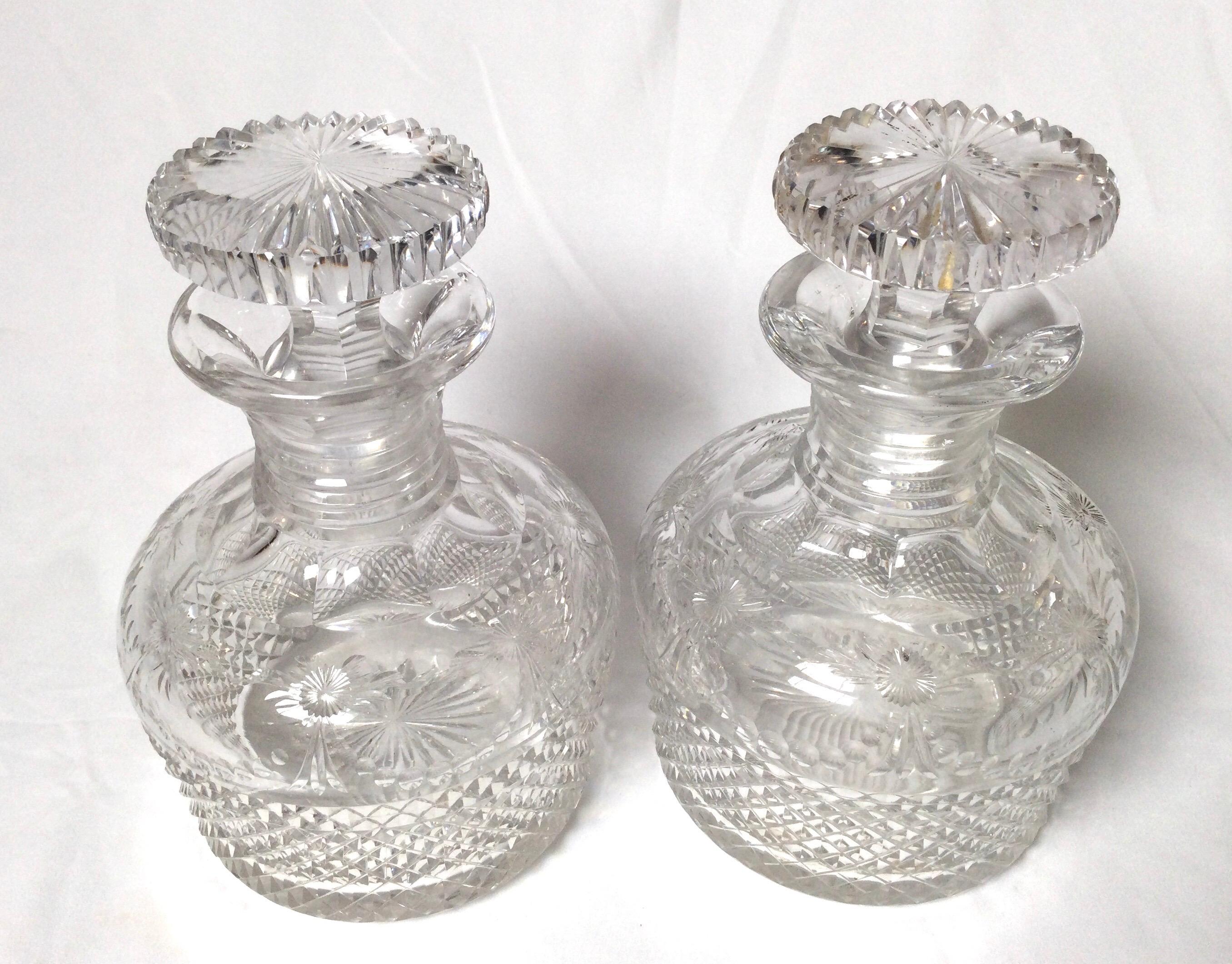 Coppia di decanter inglesi in vetro tagliato a mano con tappi originali. Condizioni eccellenti, con una leggera usura prevista sul fondo a testimonianza dell'età. Il corpo è tagliato a diamante con leggere incisioni floreali intorno al fianco verso