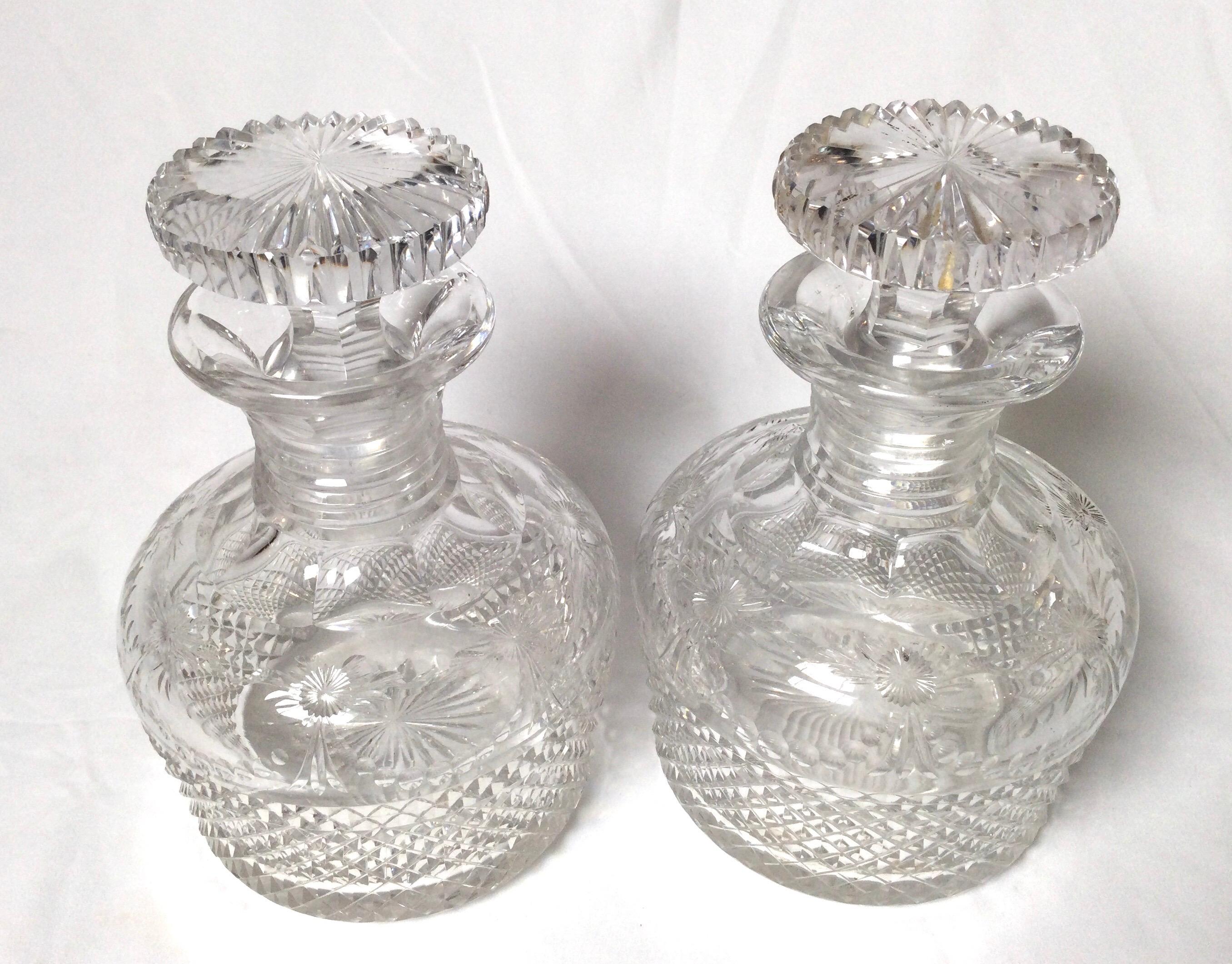 A pair of handcut glass English decanters with original stoppers. Excellent condition with light expected wear at the bottoms as proof of age. The diamond cut body with light floral engravings around the hip towards the top.