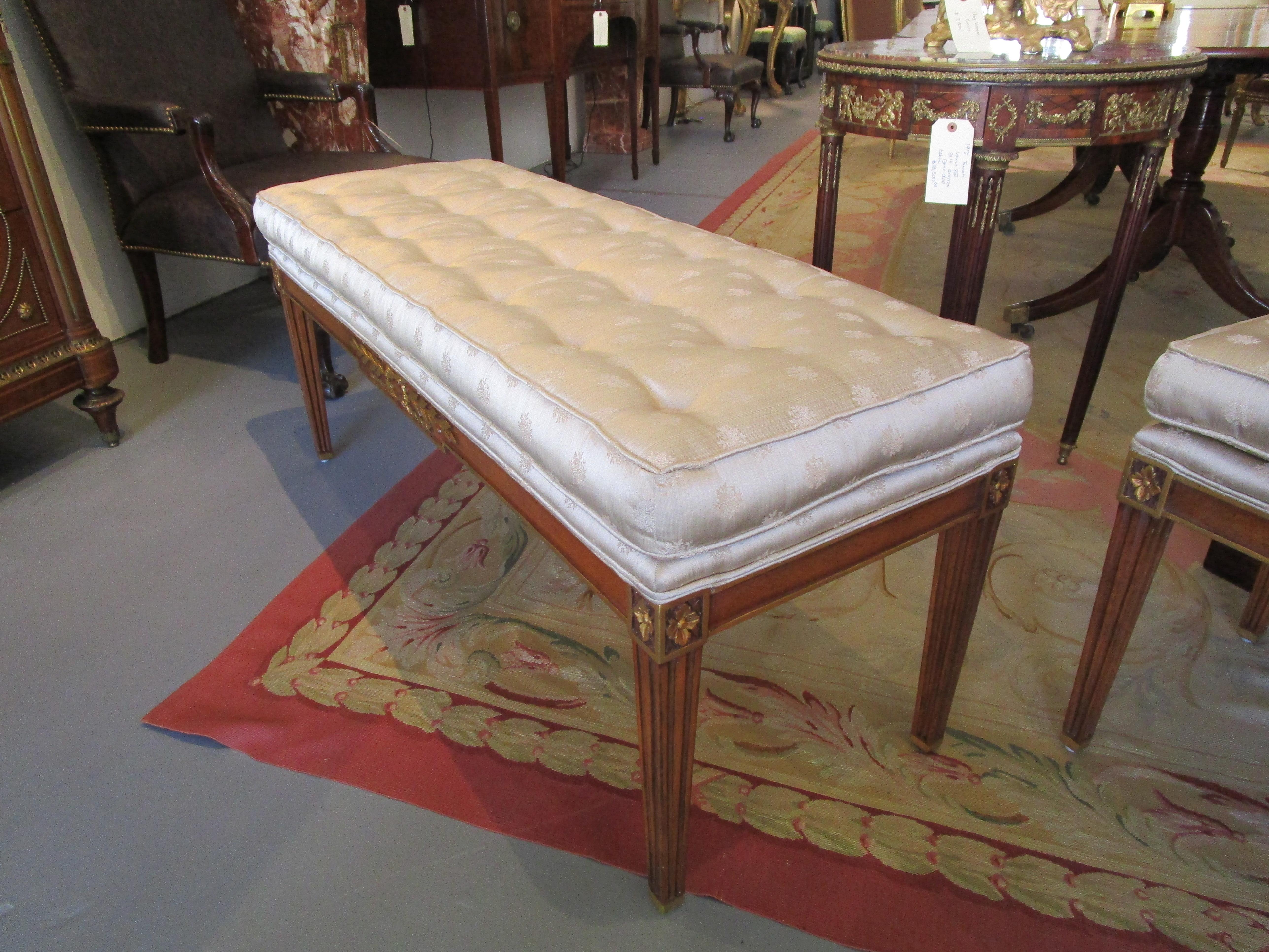 A fine late 19th century to early 20th century Empire mahogany and parcel gilt pair of benches. Tufted upholstery.