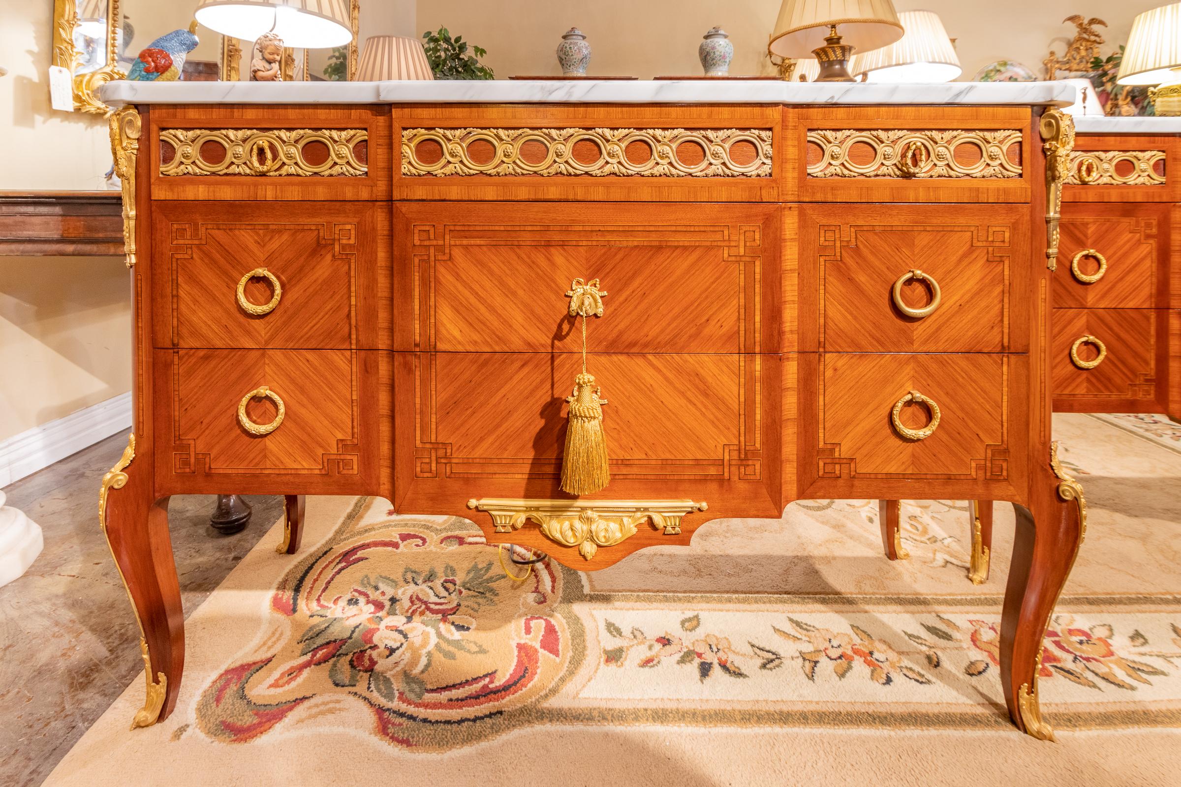 A fine pair of late 19th-early 20th century French Louis XVI kingwood and gilt bronze commodes. Original Carrara marble tops.
  