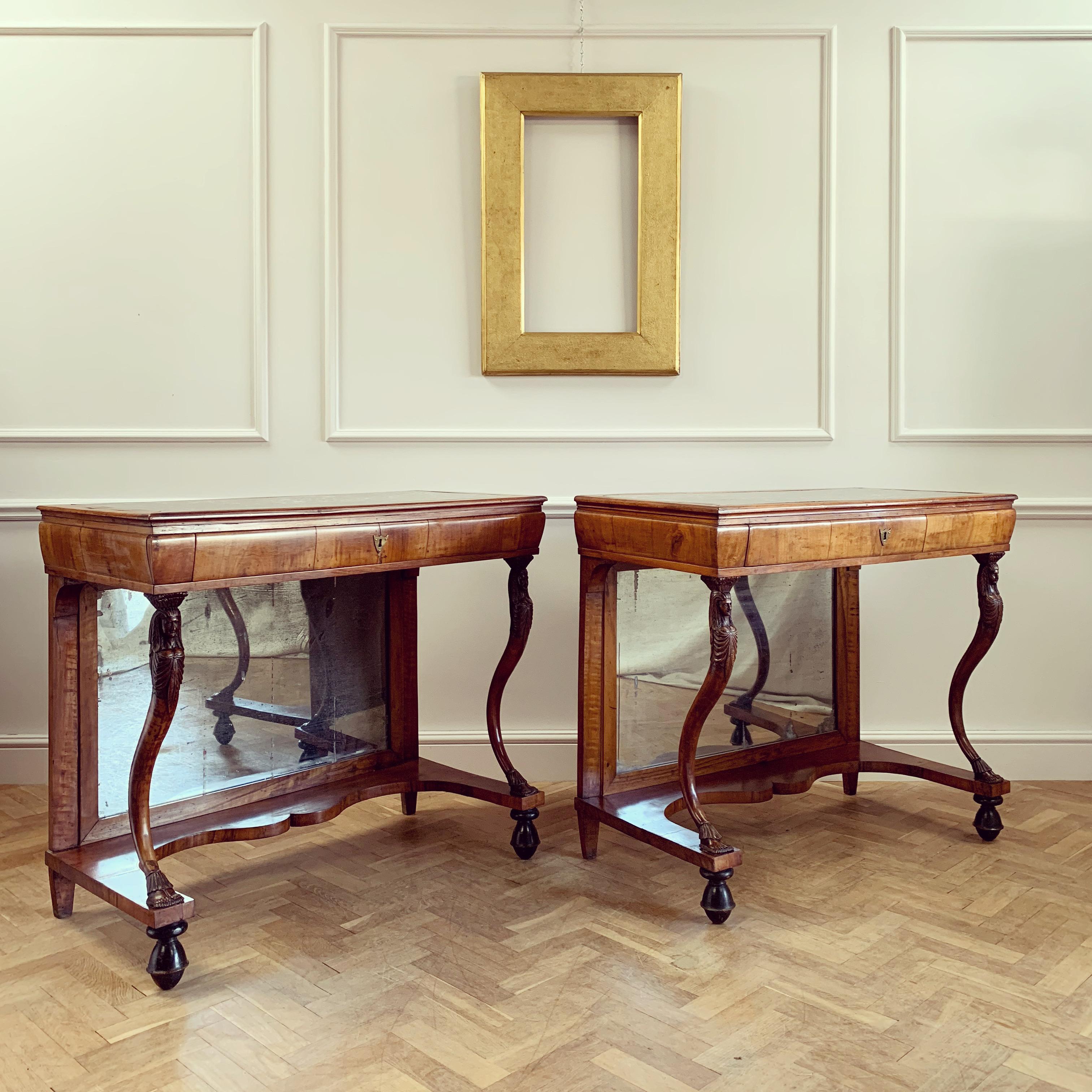 A fine pair of late eighteenth century Italian mahogany and walnut console tables with zoomorphic caryatid uprights, the back with original plate and occio de pavone marble inserts to top.