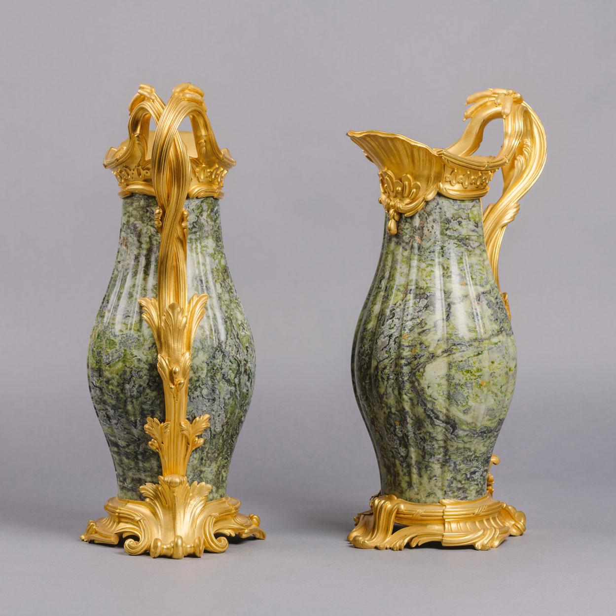 A fine pair of Louis XV Style gilt-bronze mounted marble Ewers, by Paul Sormani. 

Each ewer stamped to the underside ‘P.S.’ for Paul Sormani. 

Each ewer or 'aiguière' has a Connemara 'verte d’ireland' marble body of elongated, gadrooned