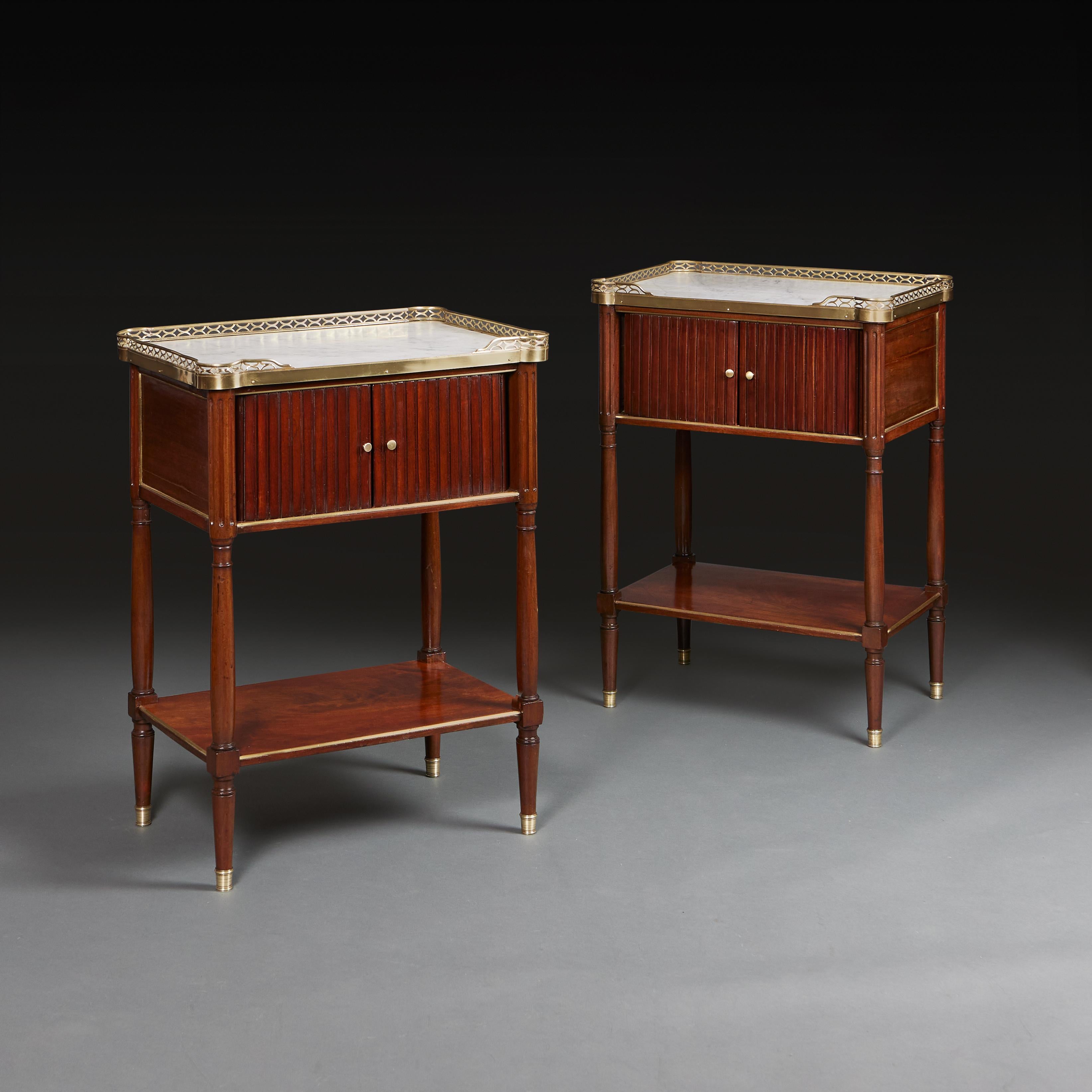 France, circa 1890

A fine pair of late nineteenth century mahogany bedside tables, with sliding tambour fronts revealing a storage space, with inset white marble tops surrounded by pierced brass galleries, with lower tier and all supported on