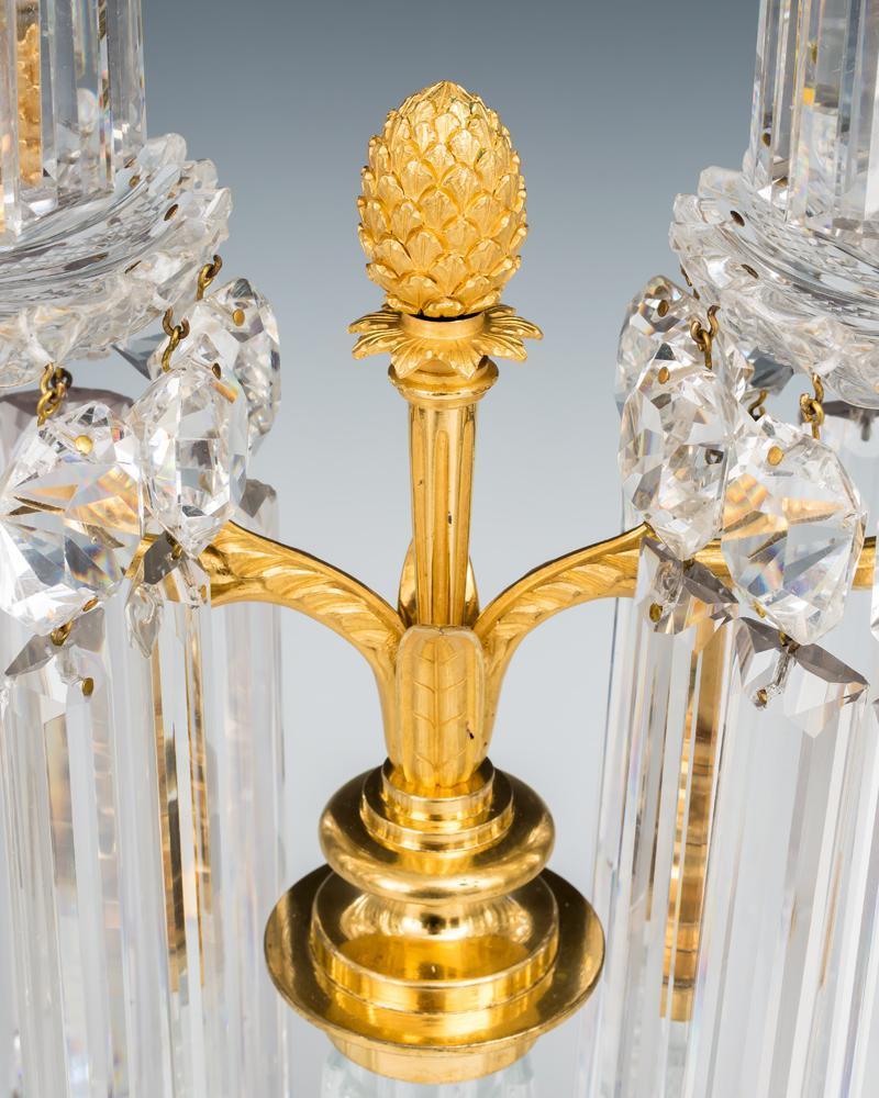 A fine pair of Regency cut glass candelabra by John Blades the radial cut bases of column form mounted with twin arm ormolu branches supporting pillar and file cut drip pans and candle nozzles hung with triple cut spangles and rule drops the