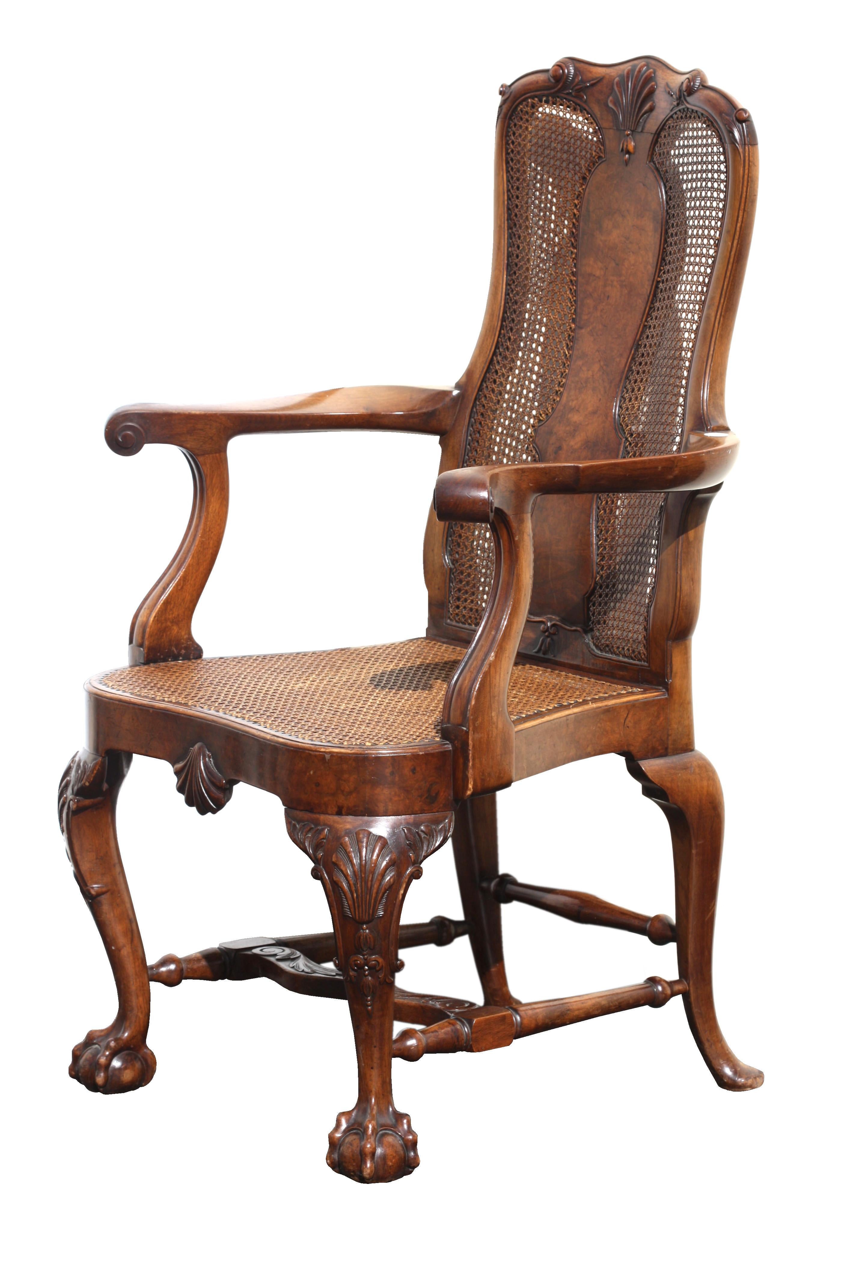 A fine pair of Queen Anne style walnut open armchairs.
Early 20th century
The shaped caned backs with solid form splats and shell-carved crestrail, raised on conforming cabriole legs united by a wavy
H-form stretcher, ending on claw and ball