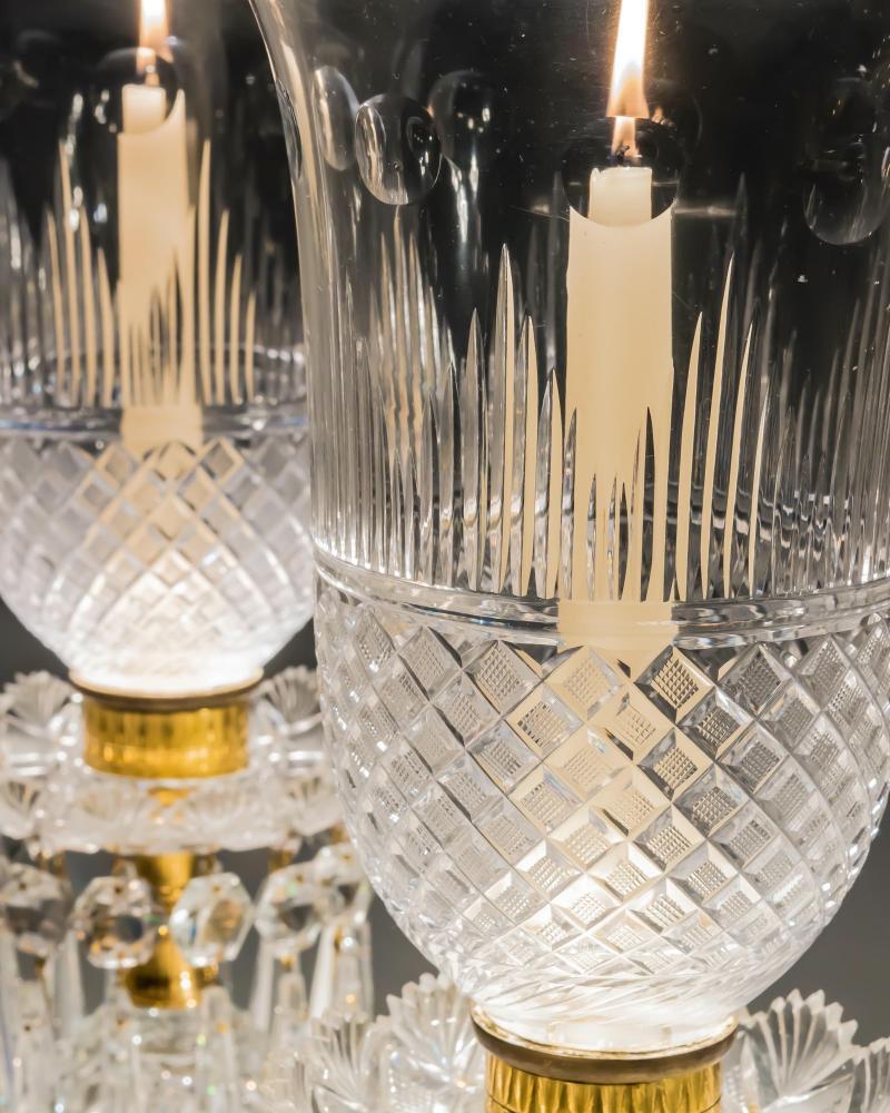 A stunning pair of Regency cut glass storm lights the radial cut bases with step cut foot supporting strawberry diamond cut eggs mounting fan edge drip pans hung with triangular icicles of rare design, the storm shades cut with strawberry diamonds