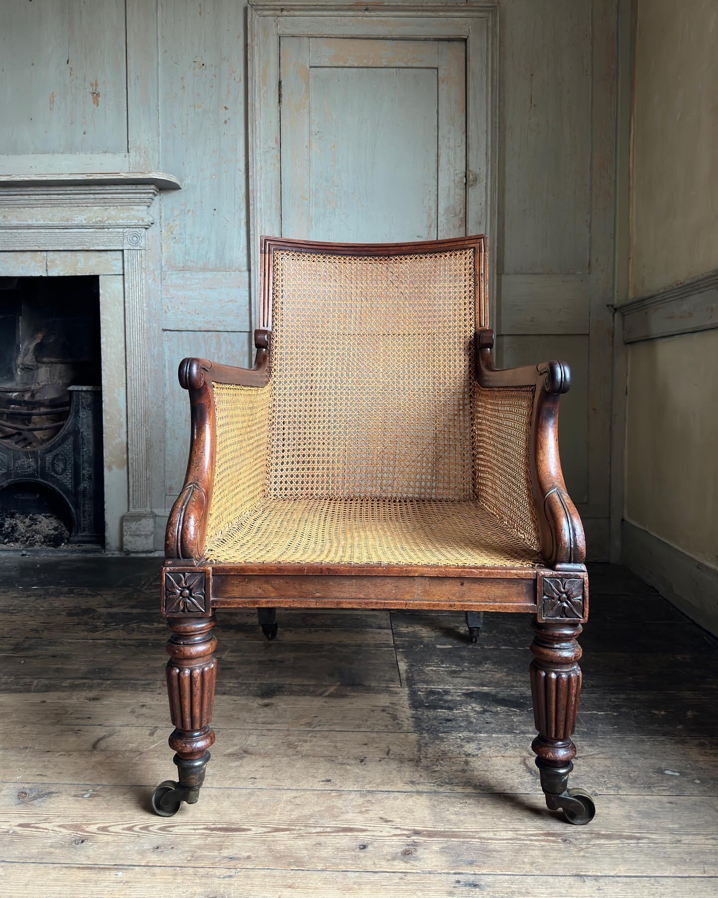 A fine pair of regency mahogany bergère armchairs of superb quality and generous scale, English, c.1815. Attributable to Gillows. The square chair back supporting scrolling arm terminals, raised on reeded & tapering front legs with flowerhead