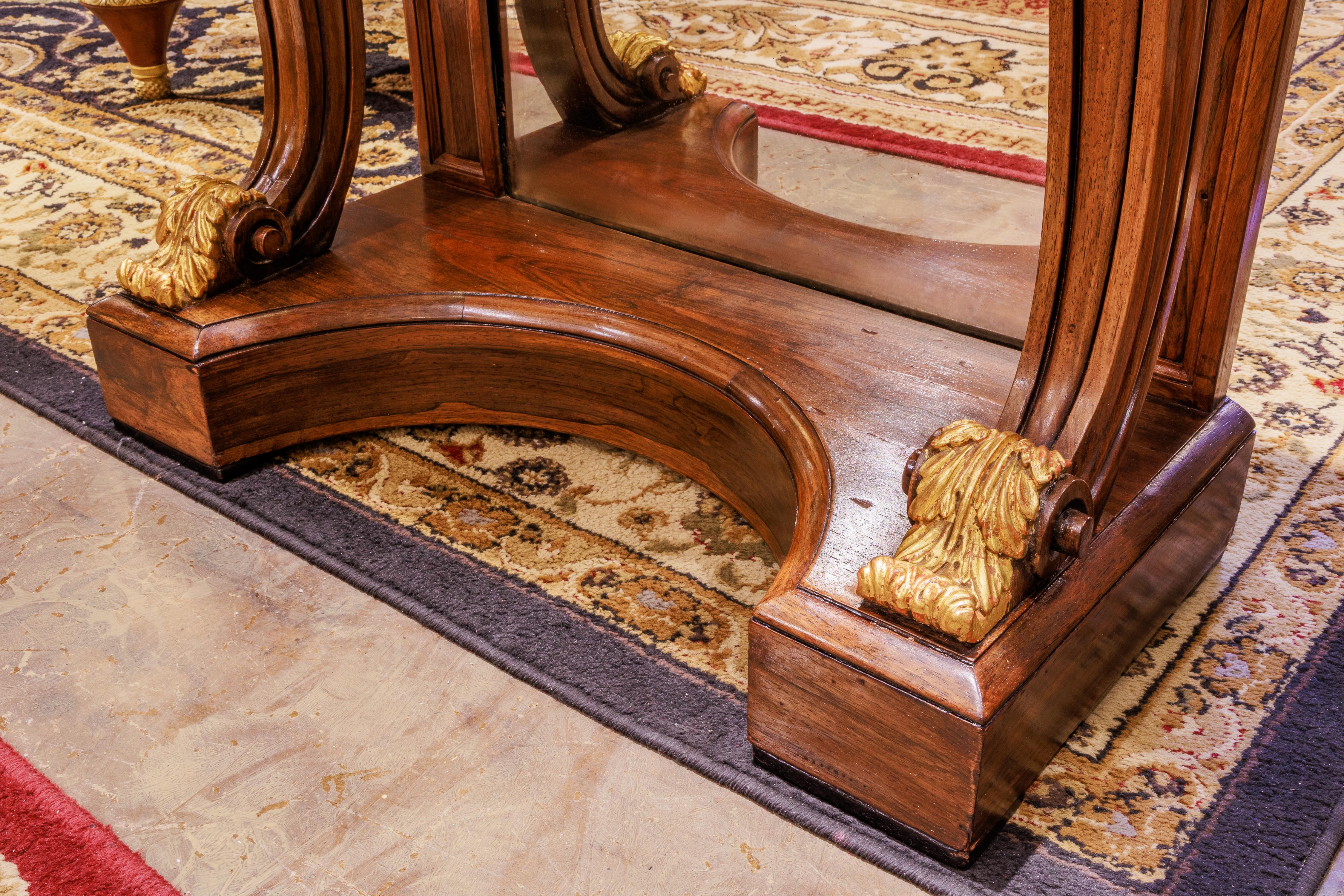 A fine pair of Regency rosewood and parcel gilt consoles. Carrera marble tops . Fine quality pair with mirrored backs . 