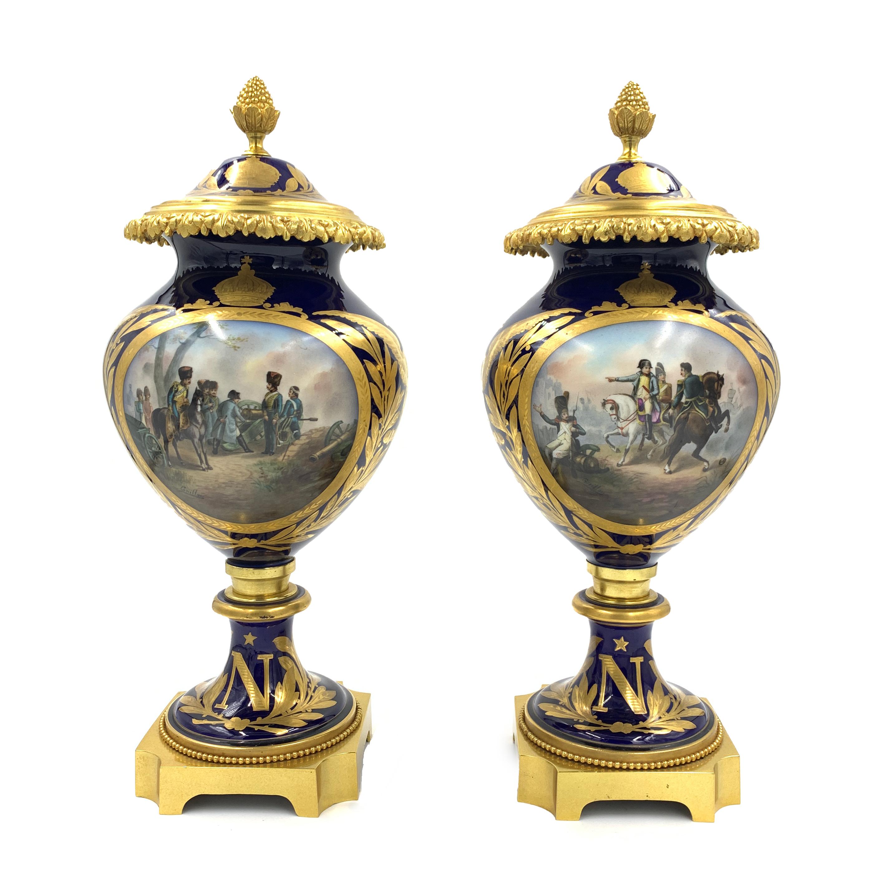 A pair of Sevres style gilt-metal mounted vases and covers decorated in the Imperial manner, circa 1900, each vase stands on a square ormolu base, painted with battle scenes, reserved on a blue and gilt ground, the base with Imperial 'N' cypher. The