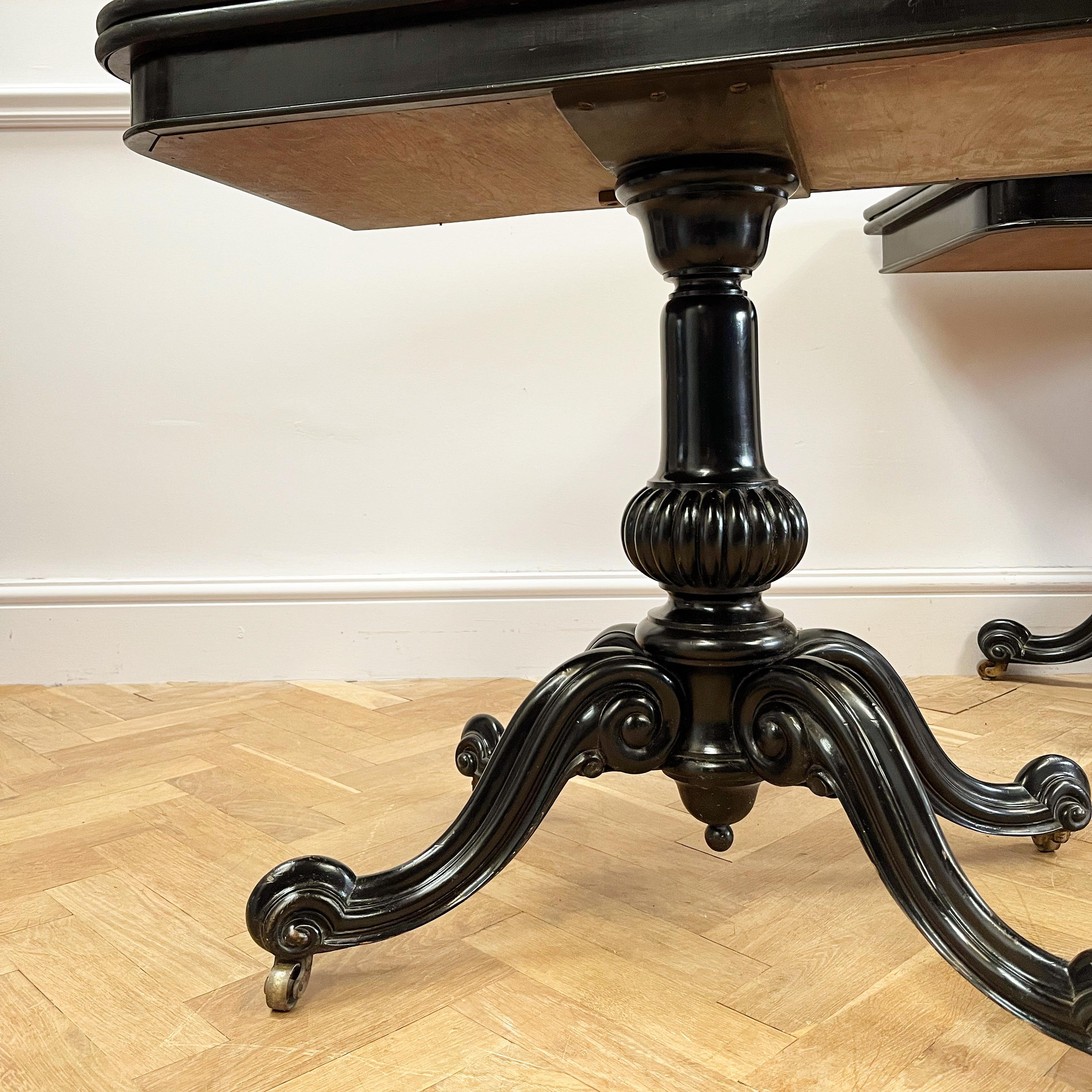 A striking pair of William IV ebonised card tables, the tops highly polished supported by a fluted baluster column above four carved legs terminating in brass castors. 

English, Mid-19th Century.