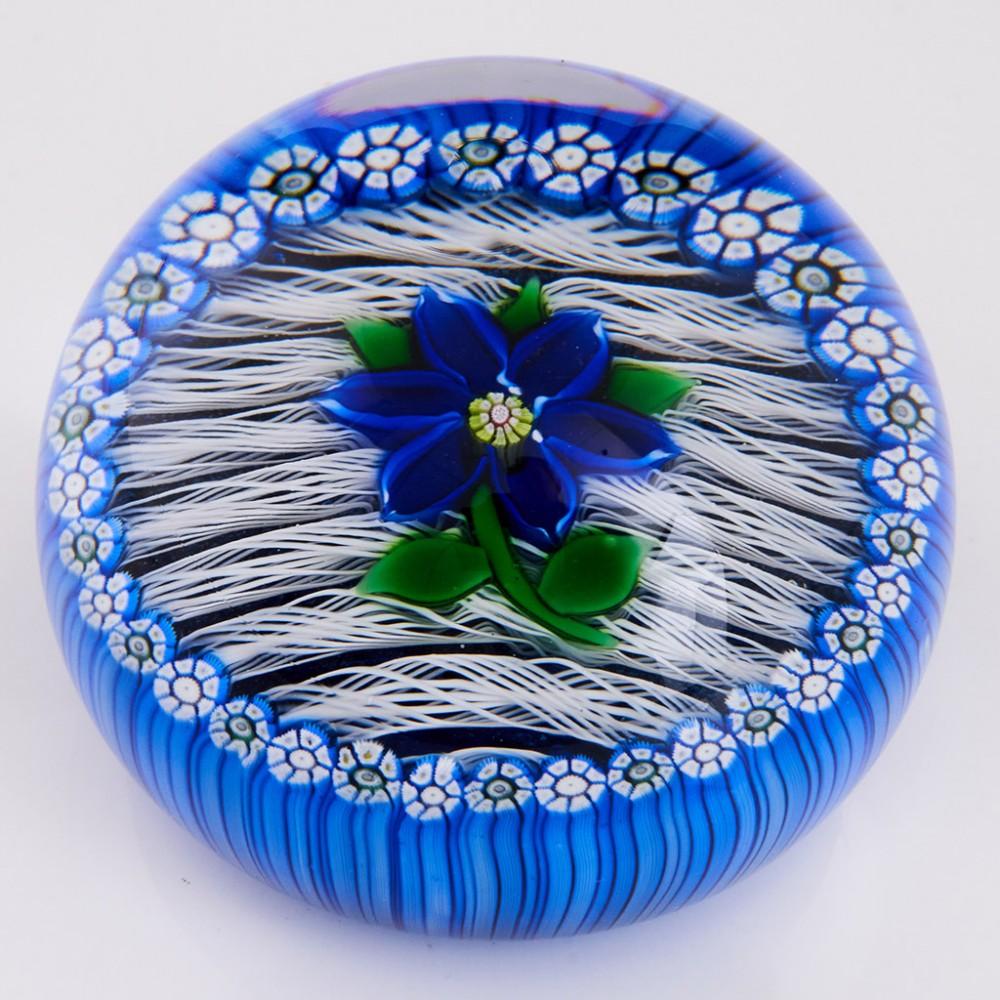 A Fine Perthshire Blue Gentian Paperweight, 1981

Additional information:
Date : 1981
Origin : Scotland
Features : A blue lampwork flower with a complex centre cane on parallel white latticino strips on a blue cushion with an outer ring of