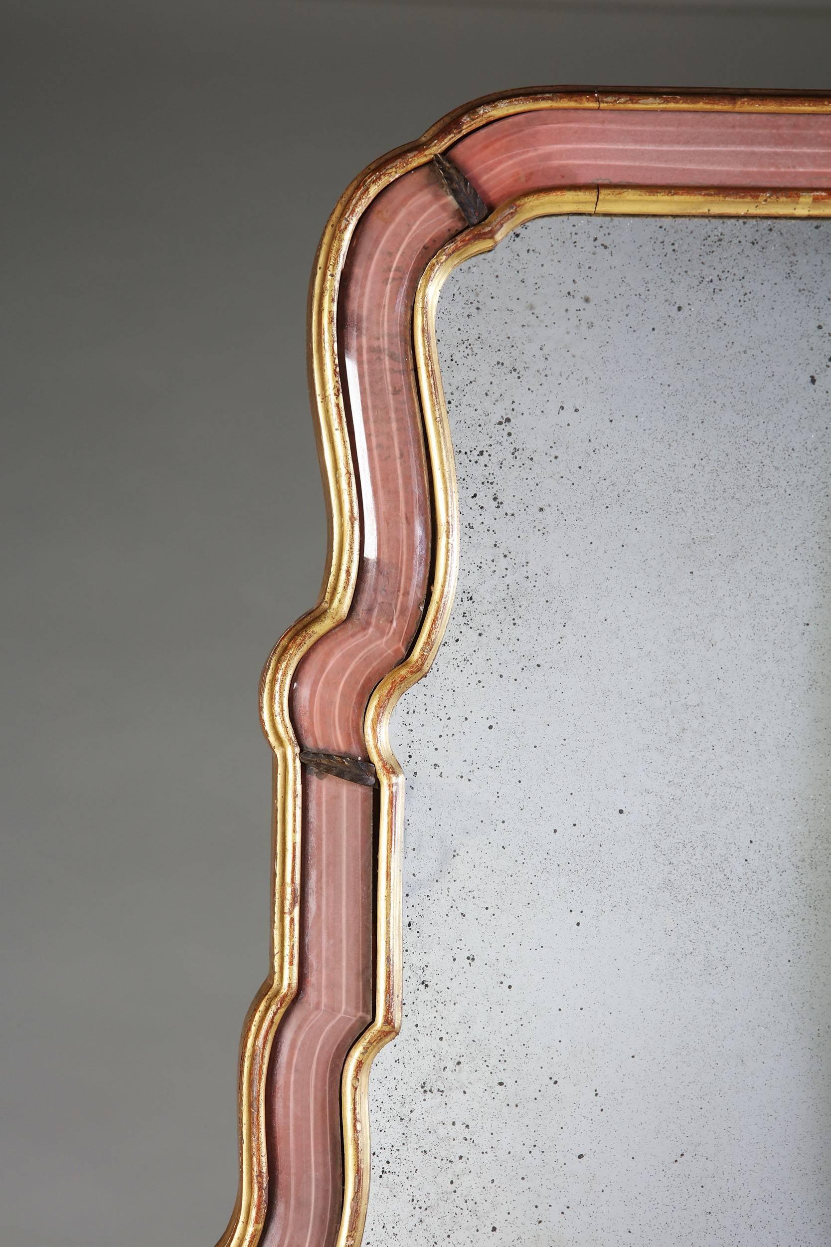 A fine Queen Anne style pier mirror attributed to Maison Baguès, with pink bevelled glass border and giltwood frame, punctuated with gilt bronze leaves.