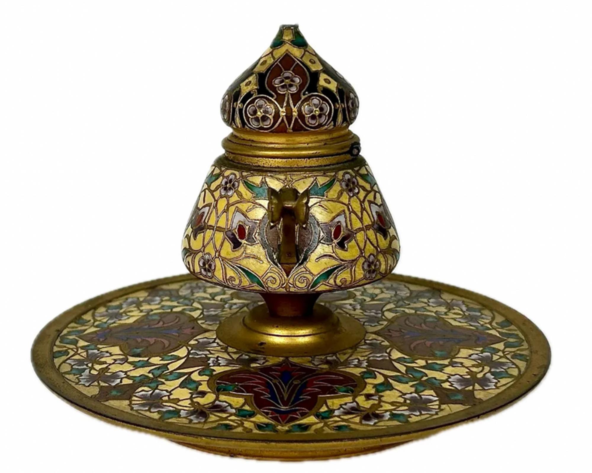 Un grande calamaio in bronzo e champlevé del XIX secolo con sfondo giallo e grandi trifogli bordeaux con motivi di foglie d'edera e fiori di ciliegio. Con coperchio incernierato, manici triangolari floreali e inserto in vetro originale.

Sul lato