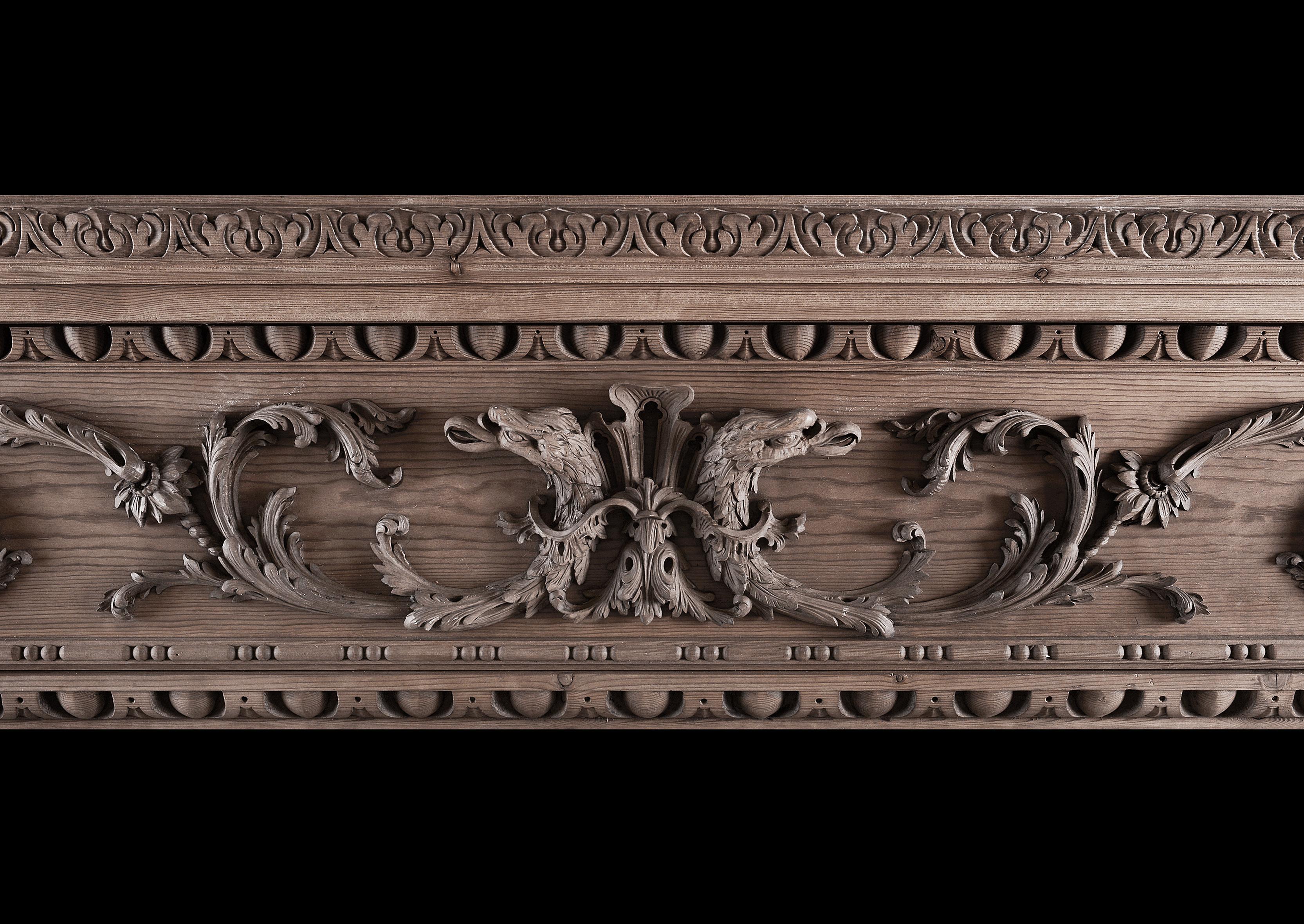 A mid Georgian style carved pine fireplace. The frieze with delicately carved scrollwork throughout, with Griffin heads to centre. The jambs with carved acanthus leaf brackets and bellflower drops. Egg and tongue and acanthus leaf mouldings to