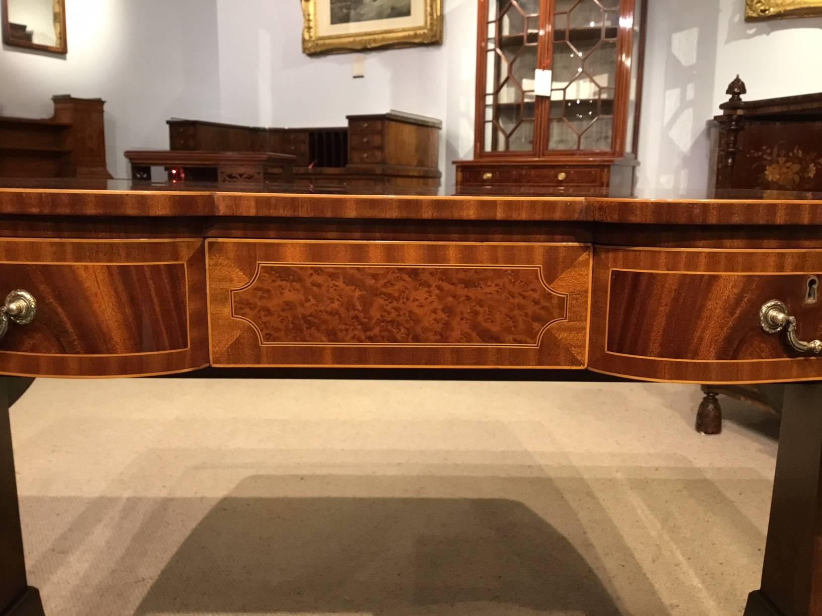 A fine quality flame mahogany Edwardian Period antique sofa table. Having a rectangular top veneered in beautifully figured flamed mahogany with boxwood line inlaid detail and banded in mahogany, above the serpentine front with three oak lined