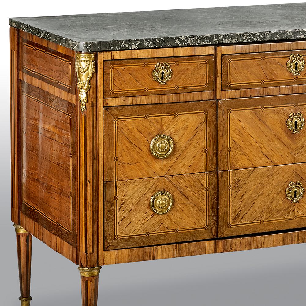 A French ormolu-mounted tulipwood, rosewood and kingwood marble top commode chest of drawers. The whole is raised on four tapered and ormolu-mounted feet above three long graduated oak-lined drawers.