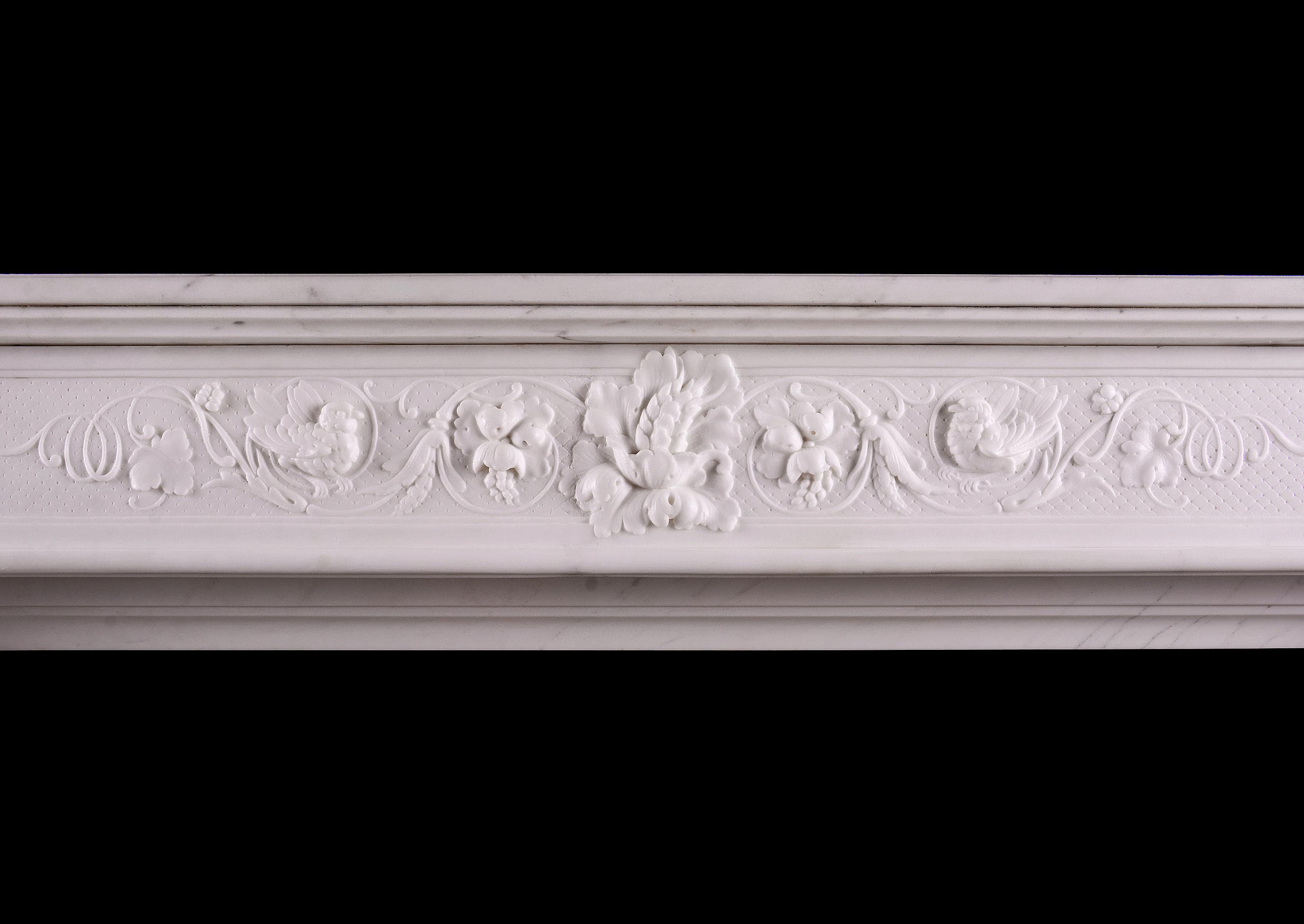 A fine quality French Statuario marble fireplace in the Louis XVI style. The tapering jambs with carving throughout surmounted by carved capitals featuring cartouche and foliage. The frieze with carved scroll work throughout, flanked by carved