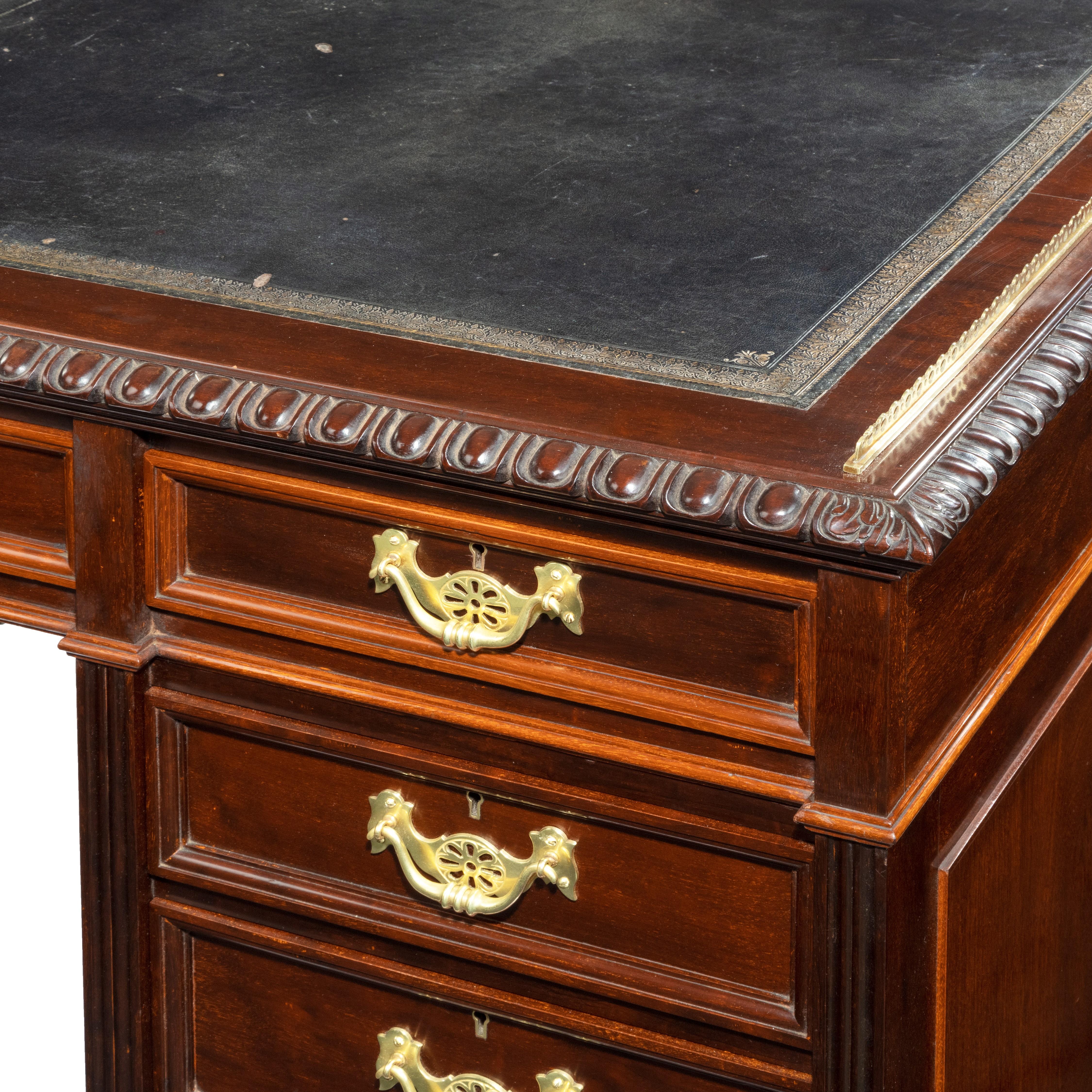A fine quality late Victorian mahogany pedestal desk, the leather-inset top with a gadrooned edge and a brass gallery on two sides, all above one long and two short frieze drawers, the kneehole with three further graduated drawers on each side, each